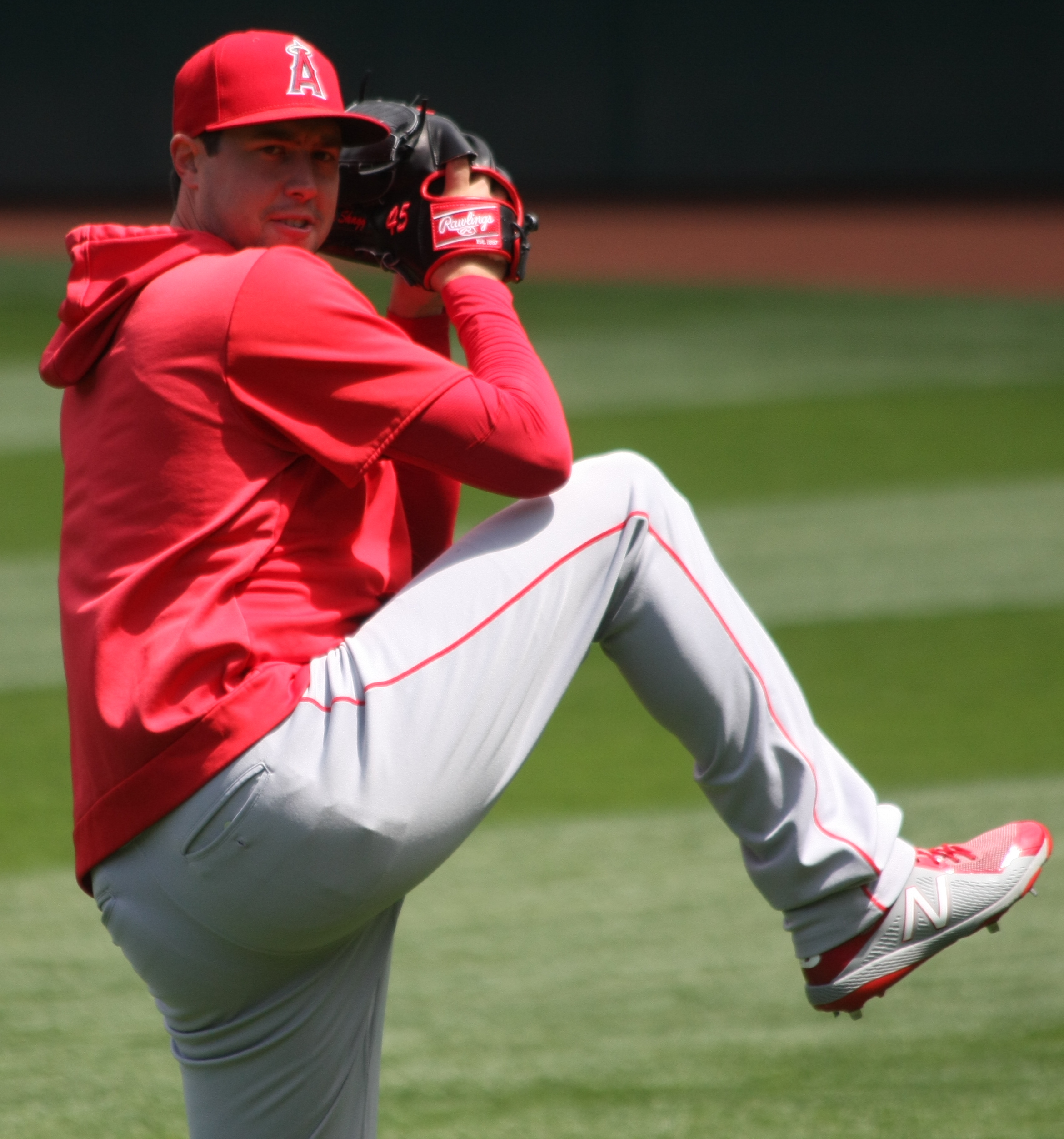 Baseball pitcher in a red Los Angeles Angels uniform mid-windup with leg raised.