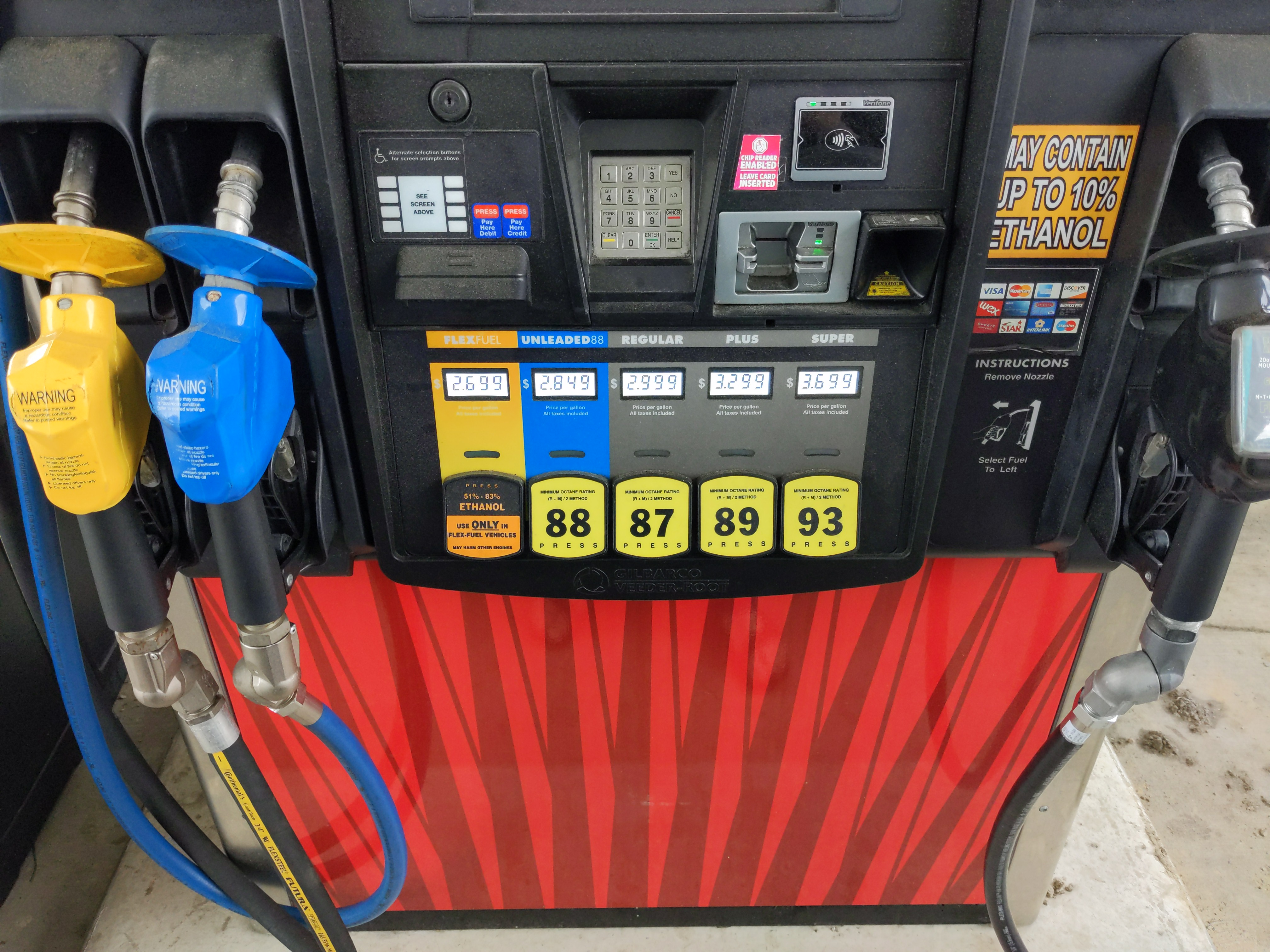 Close-up of a gas pump with three colored nozzles for E85, E15, and regular gasoline.