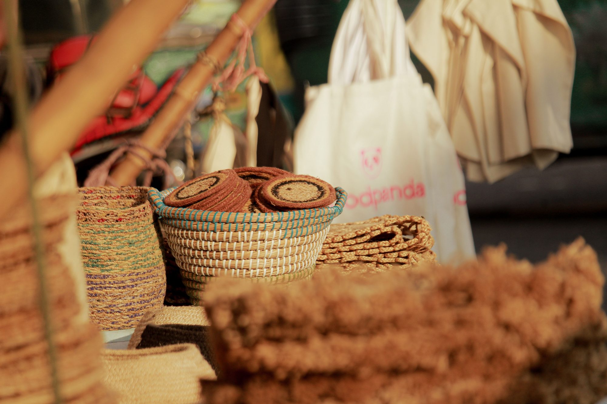 A collection of handcrafted woven baskets and coasters displayed at an outdoor market, showcasing artisanal craftsmanship.