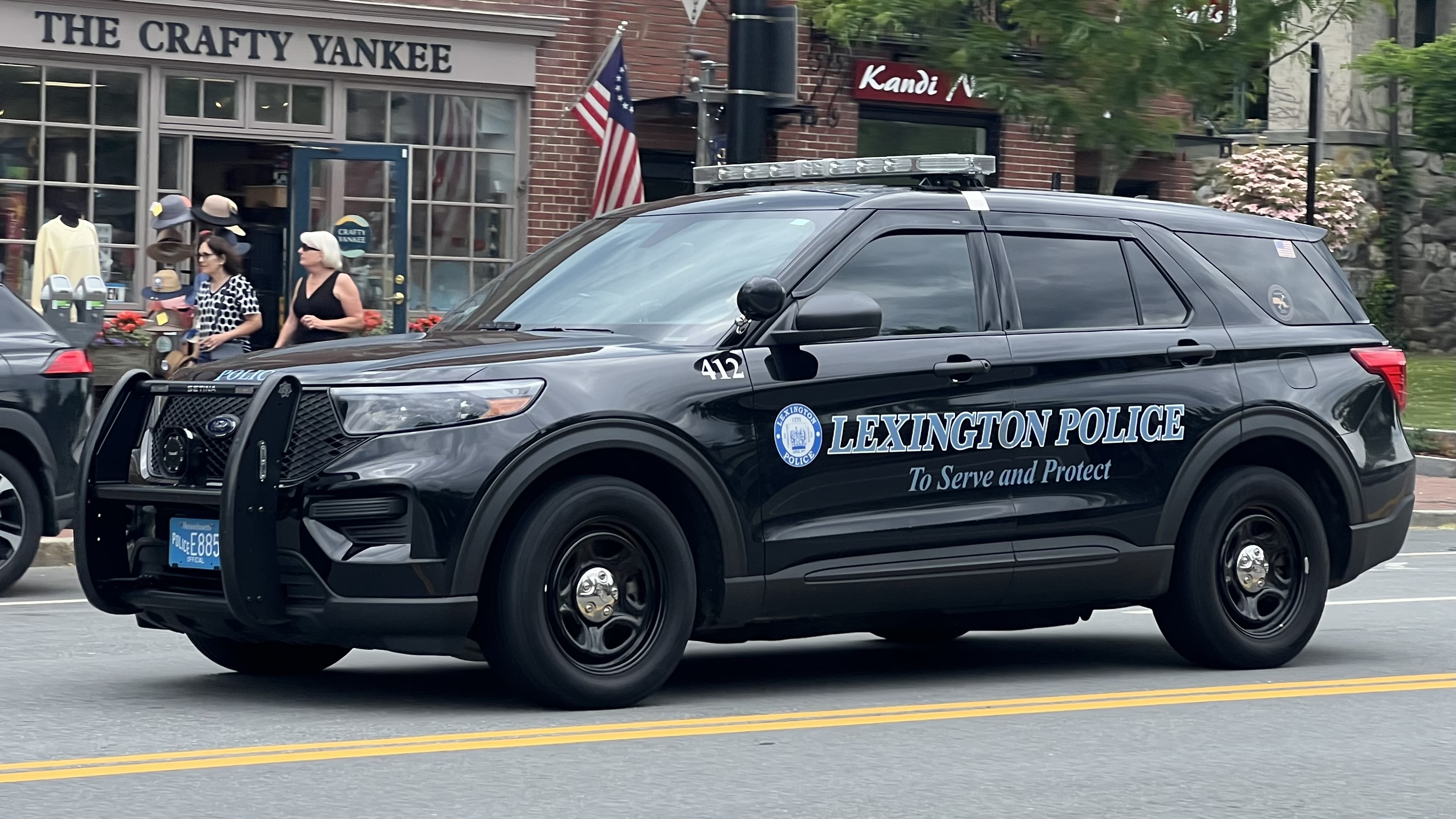 A marked black police SUV parked on a town street with storefronts behind it.
