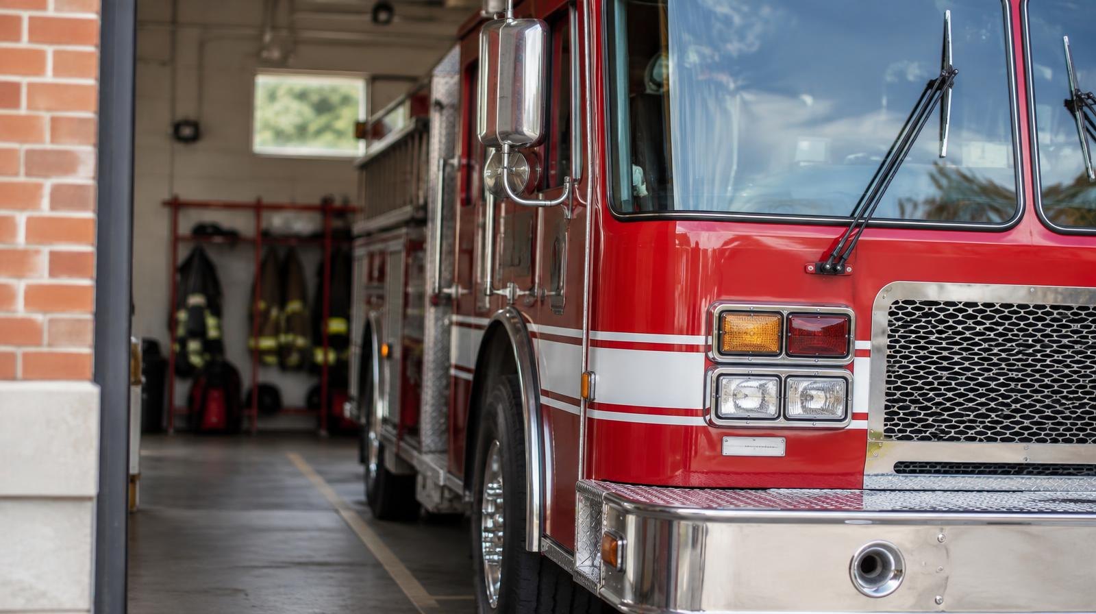 A red fire truck parked inside an open fire station bay.