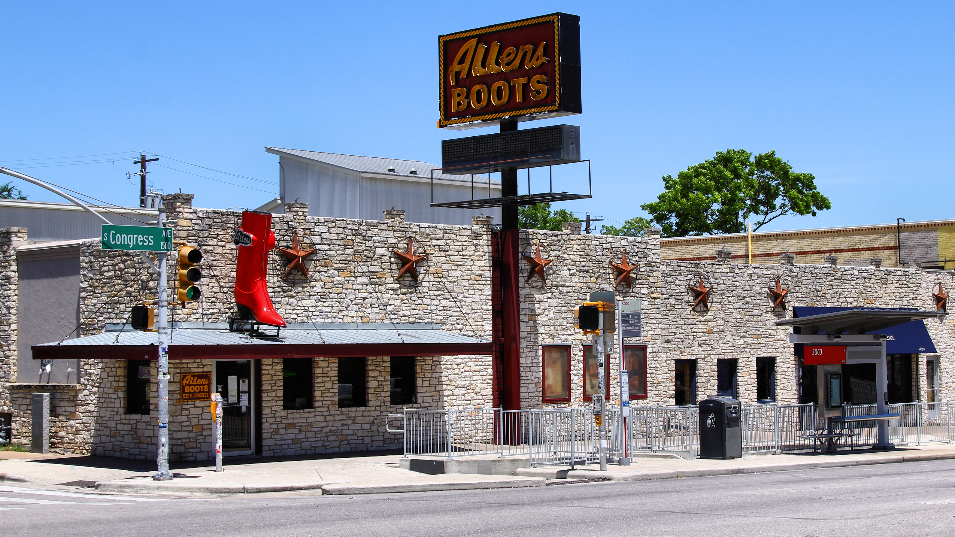 Exterior of a Western wear store with a stone facade and large red boot sculpture.