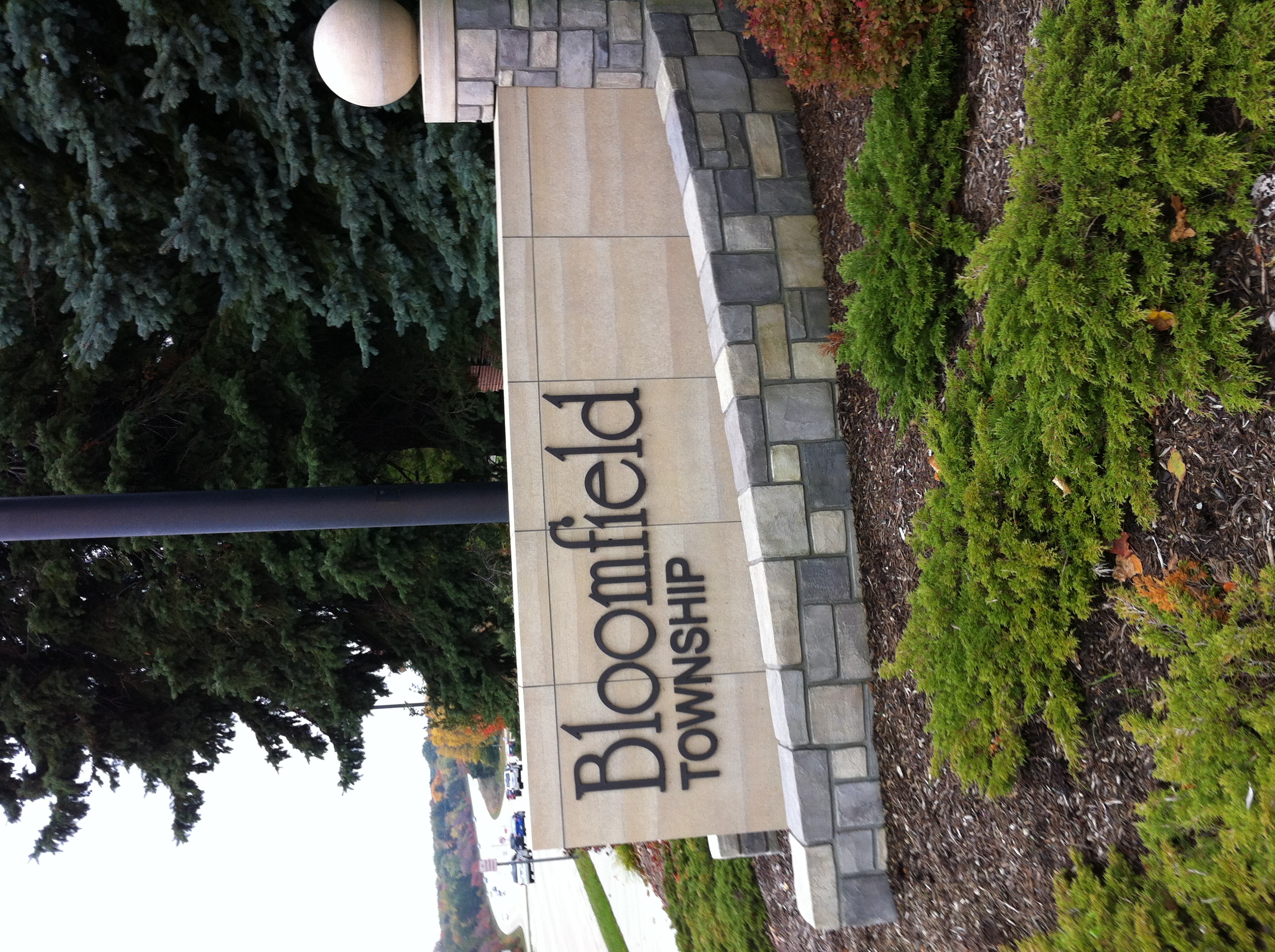 Stone masonry gateway sign reading Bloomfield Township on a landscaped roadside.