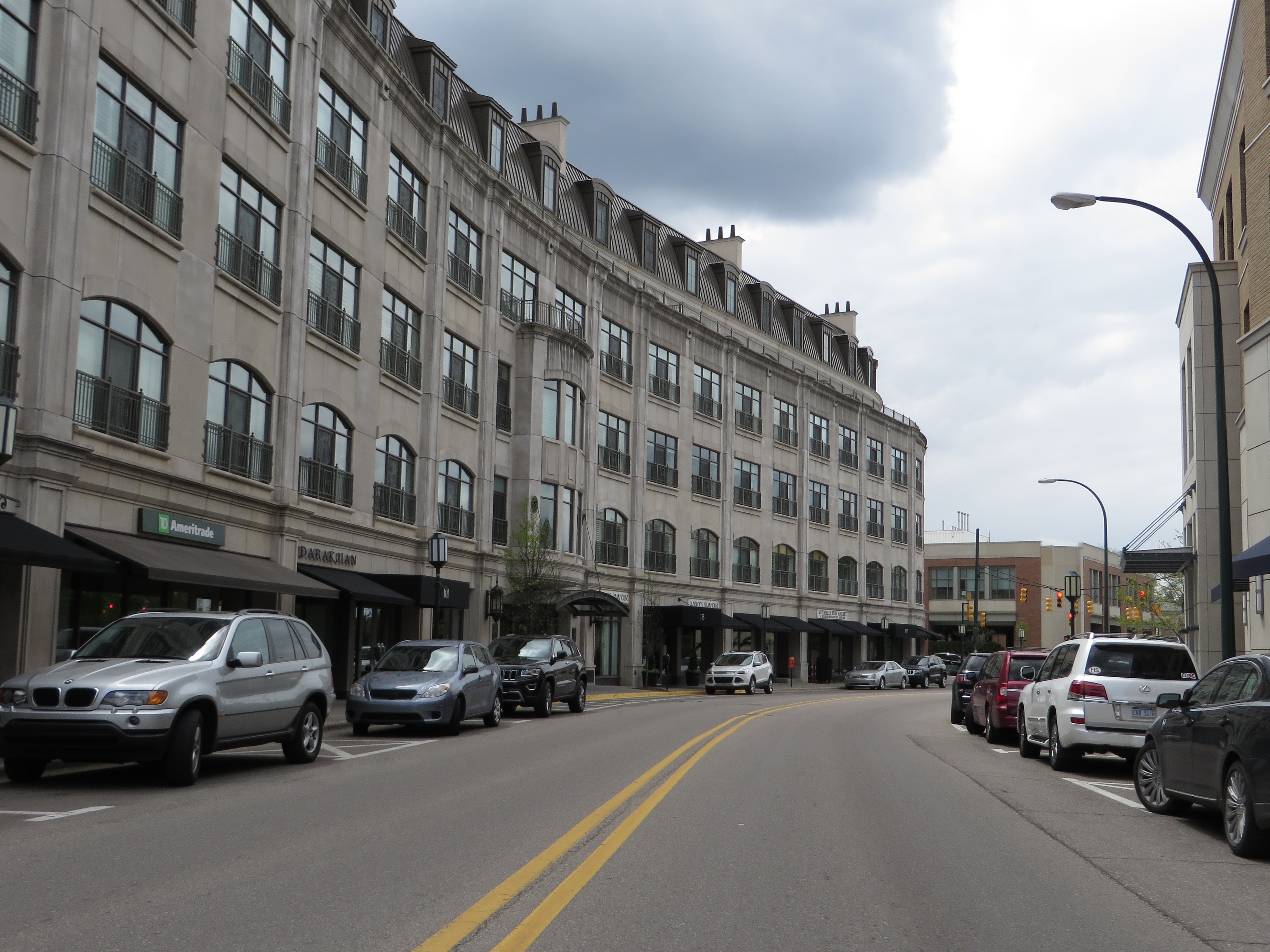 Multi-story commercial building lining a downtown street with parked cars under an overcast sky.
