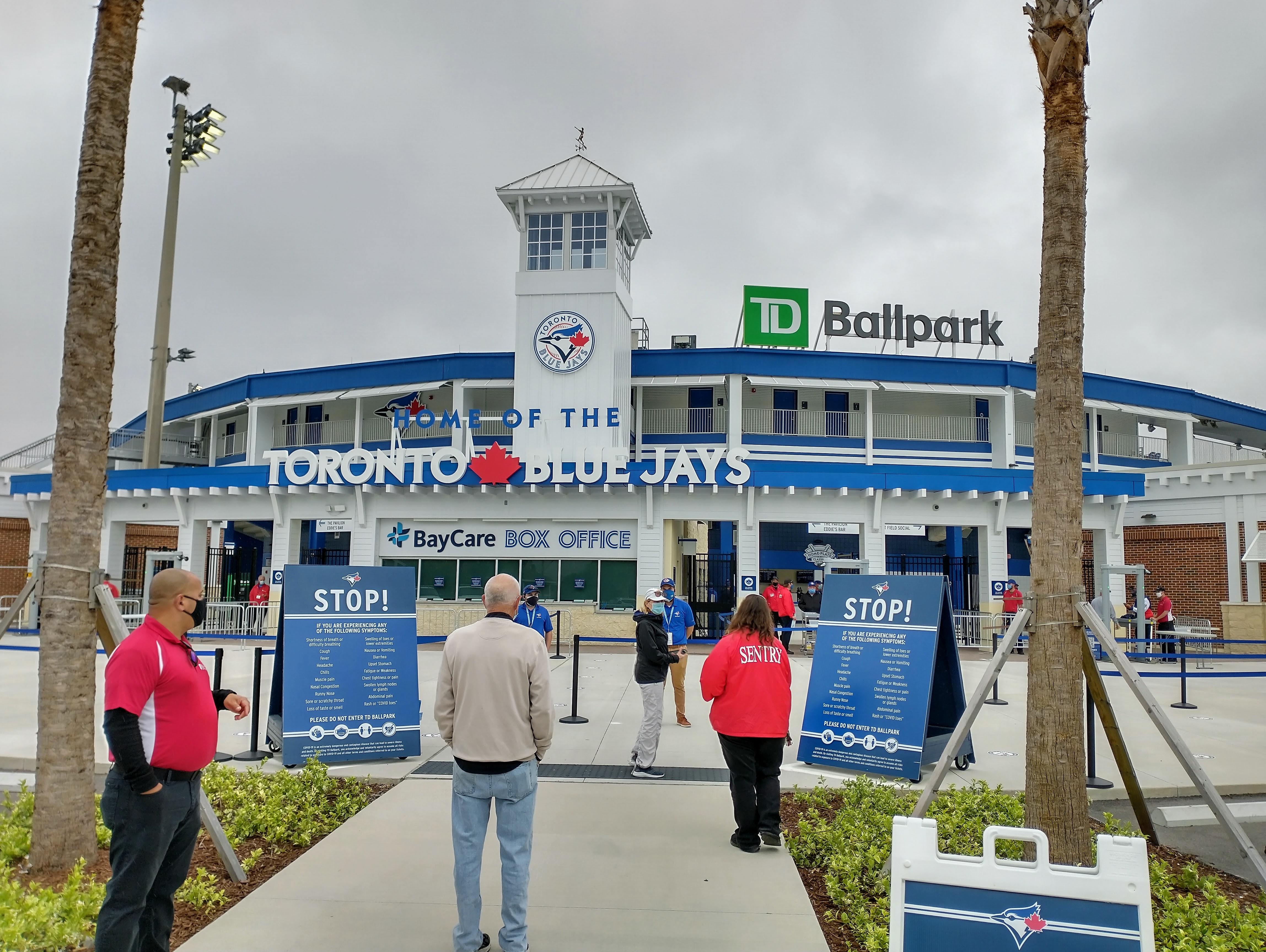 Exterior entrance of a baseball stadium with Blue Jays signage and palm trees.