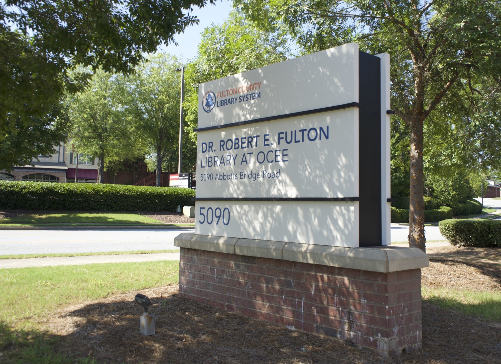 Monument sign for a public library branch outside a landscaped building entrance.
