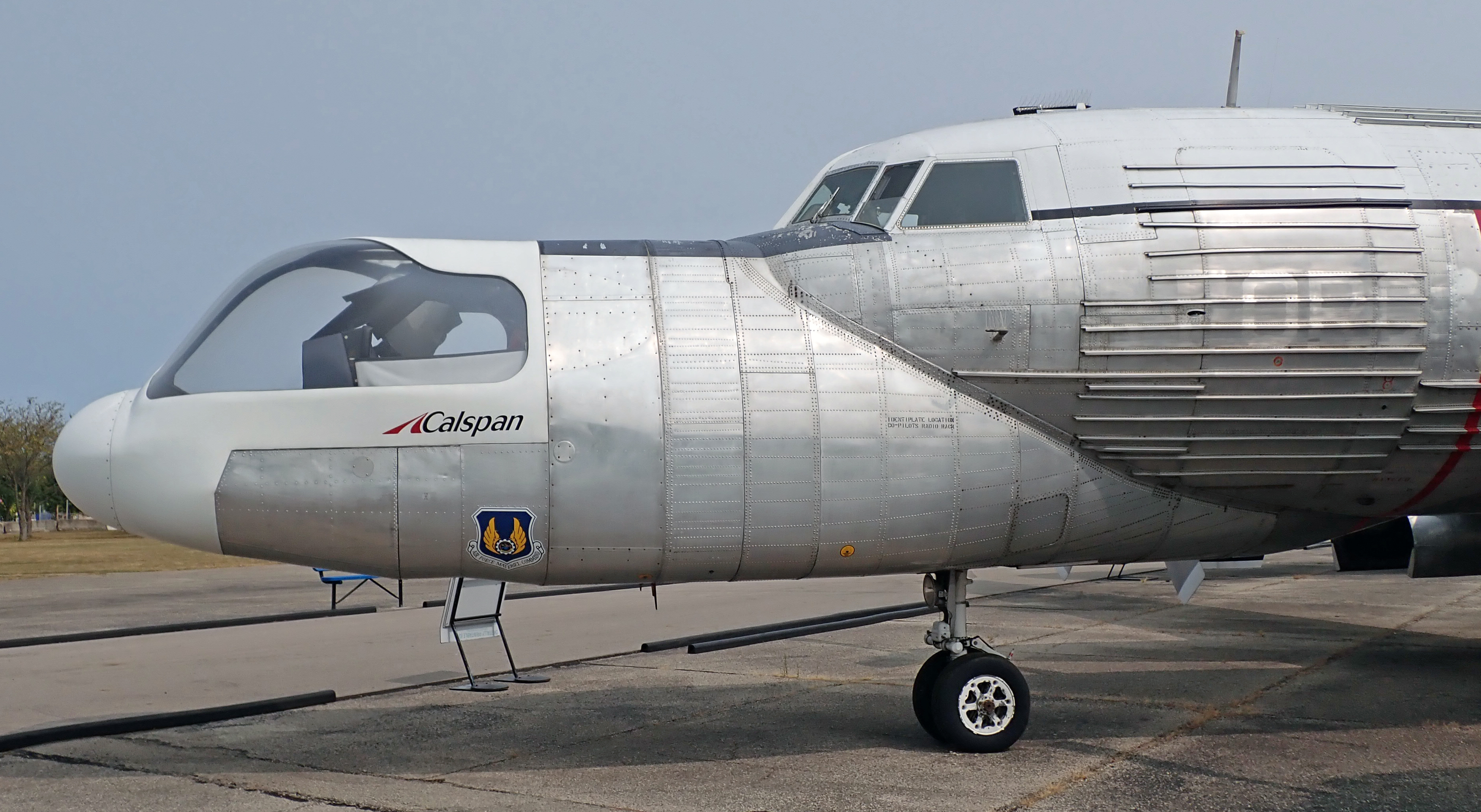 Modified military aircraft with a second cockpit on the nose parked on a tarmac at an air force museum.