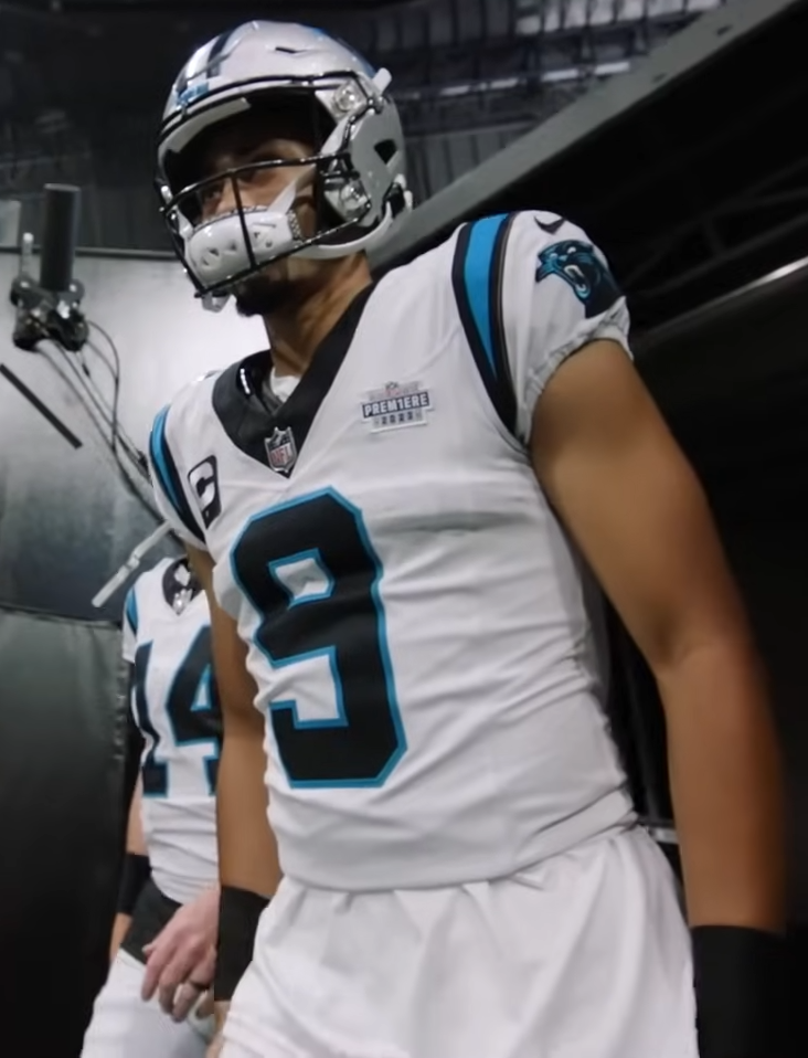 Football player in white Carolina Panthers jersey number 9 walks through a stadium tunnel.