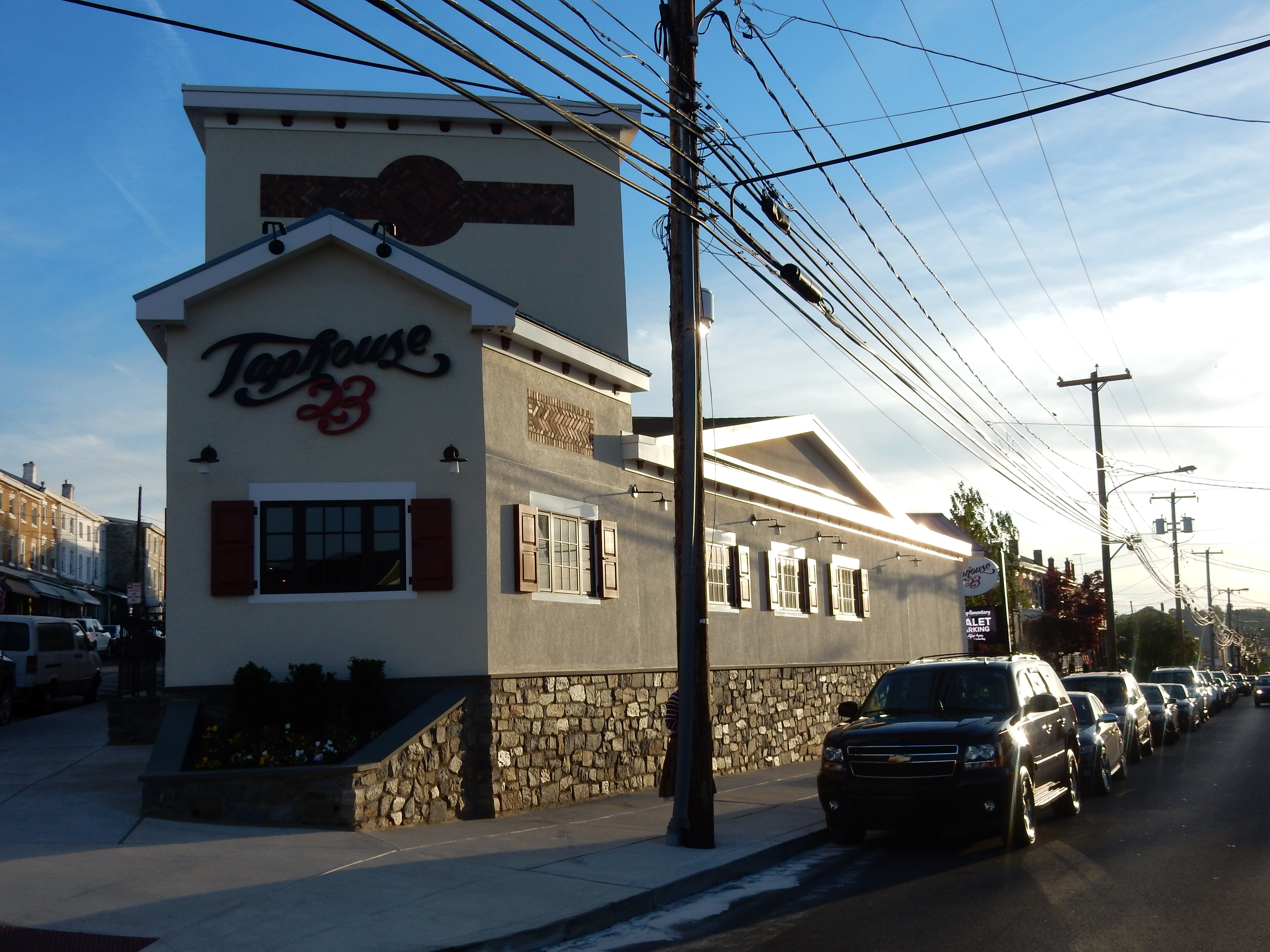 Two-story stucco restaurant building with tower facade, stone base, and red shutters.