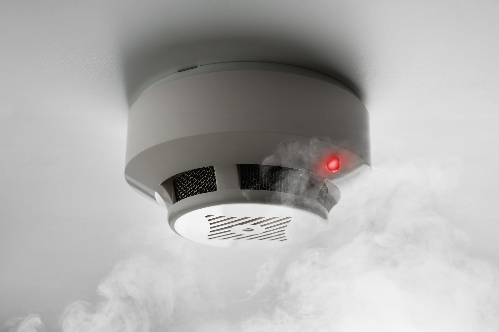 Fire alarm system detector on ceiling triggered by smoke