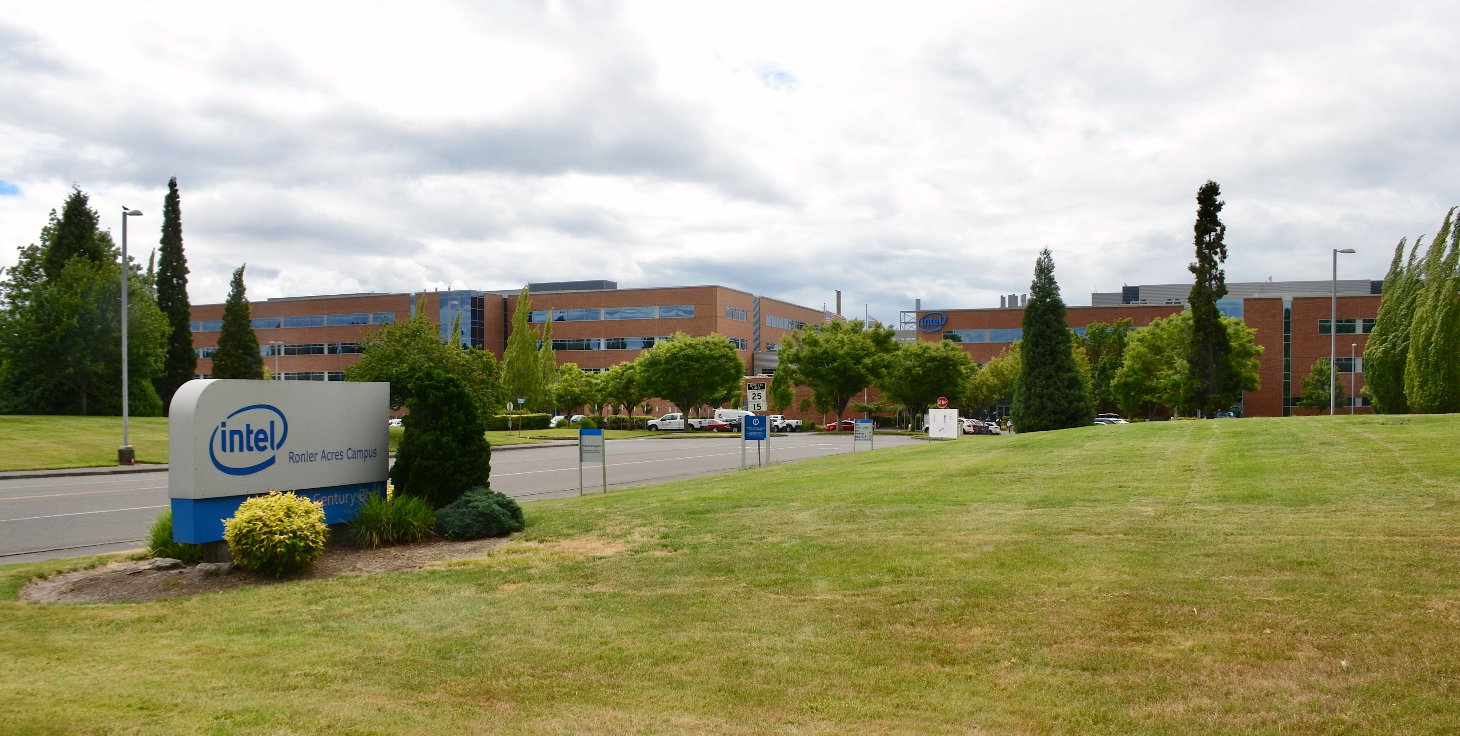 Intel Ronler Acres campus entrance sign and brick office buildings under a cloudy sky.