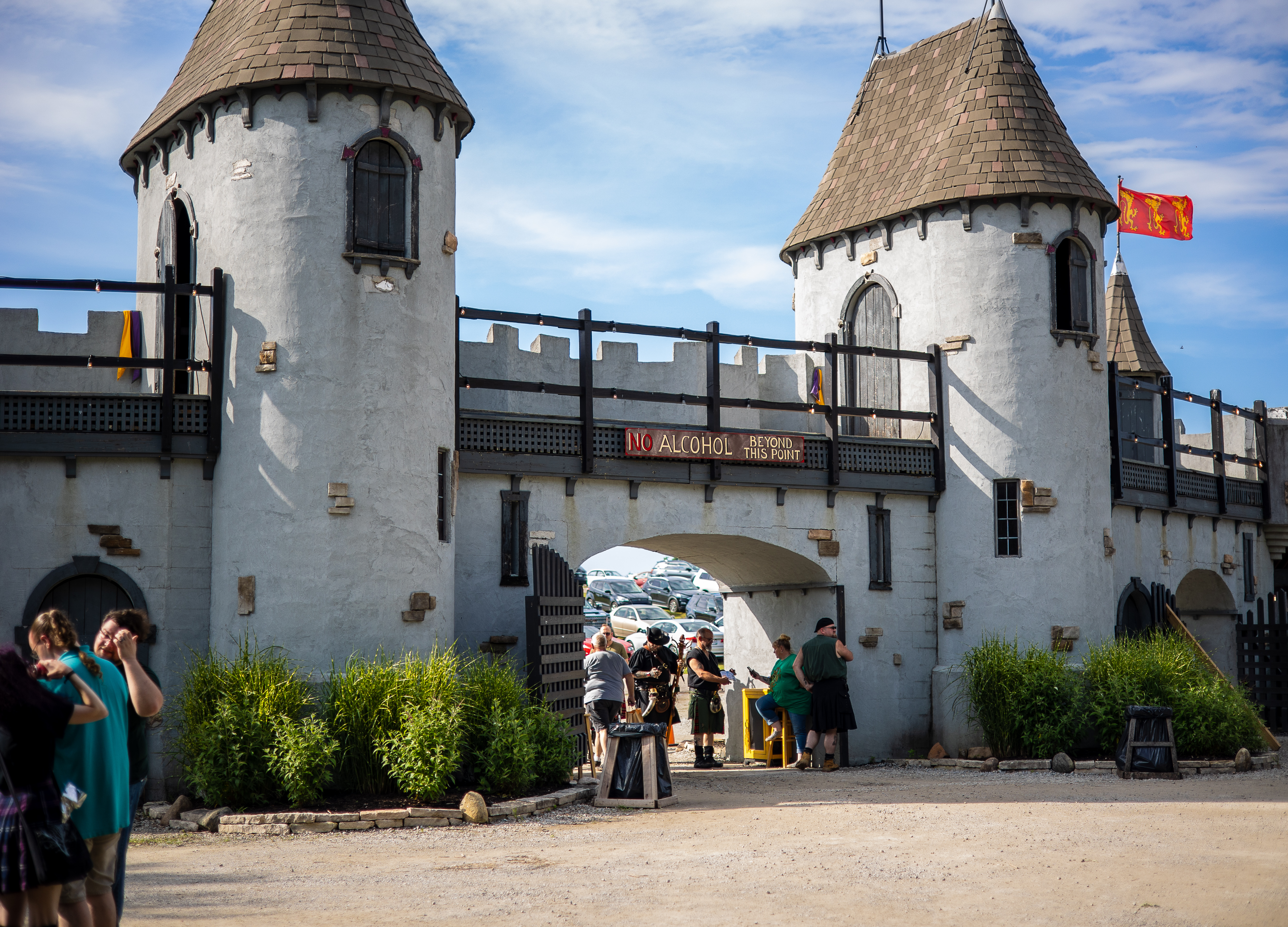 Castle-style entrance gate with two white towers at an outdoor Renaissance festival.