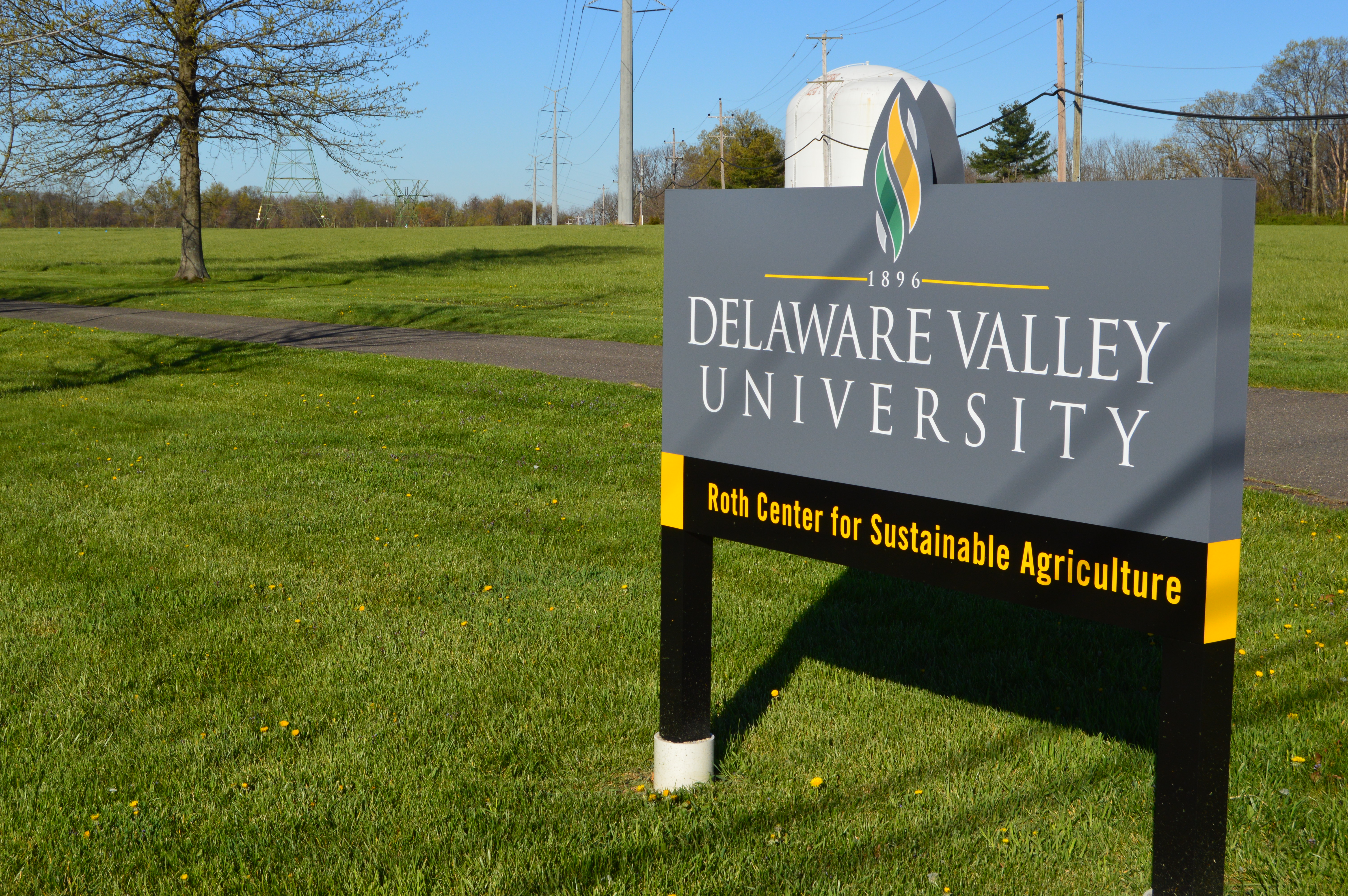 Outdoor sign reading Delaware Valley University with a yellow banner below.