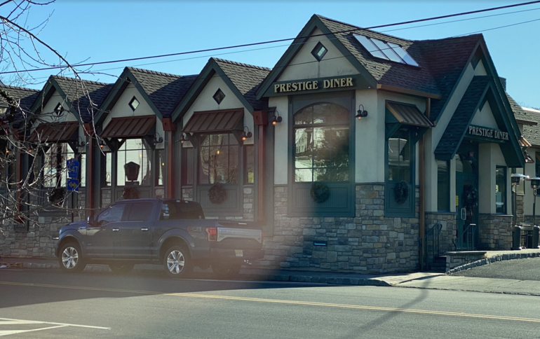 Stone and wood exterior of Prestige Diner with peaked rooflines and signage visible.