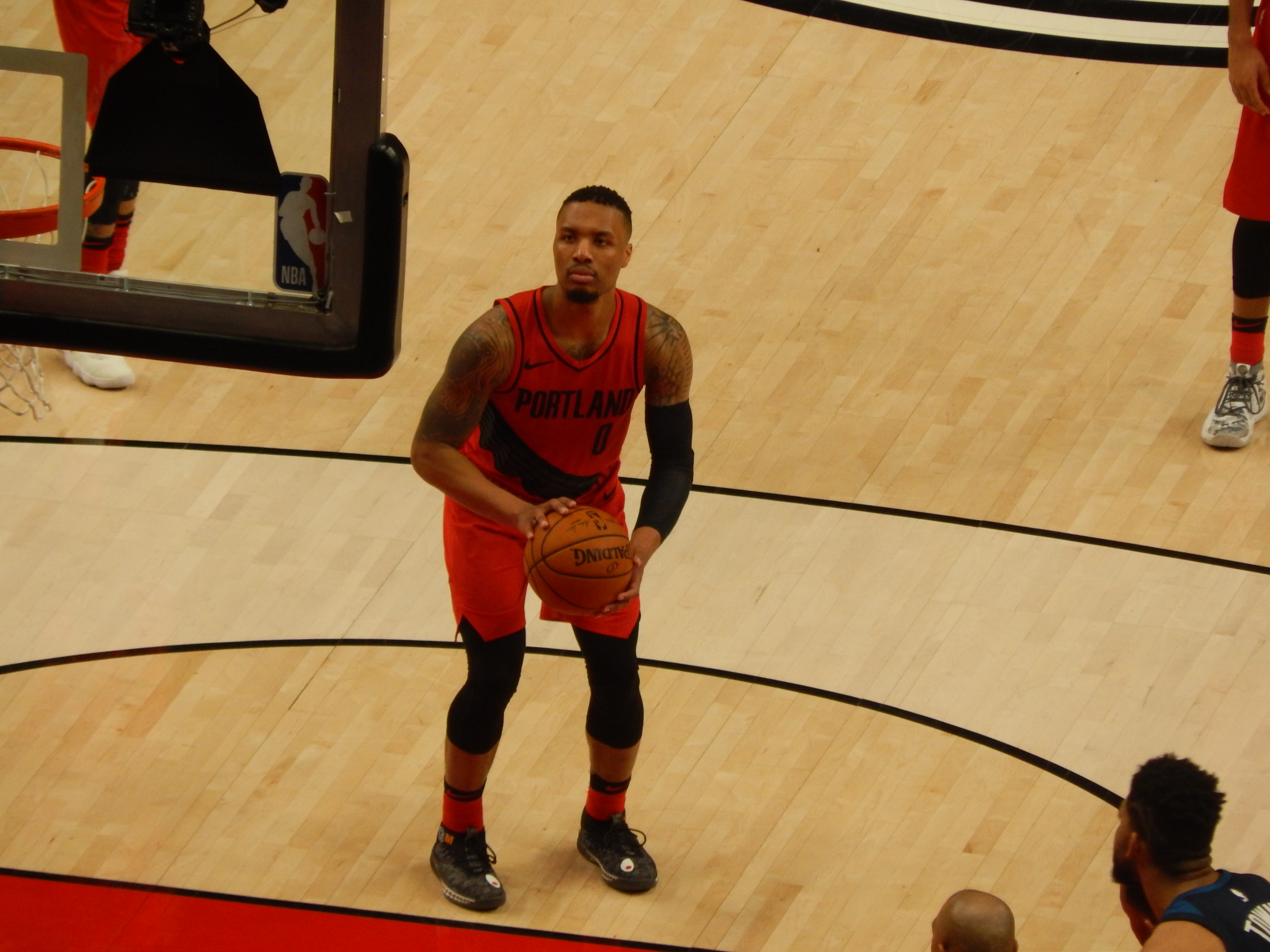 Basketball player in a red Trail Blazers jersey holding a ball on a hardwood court.