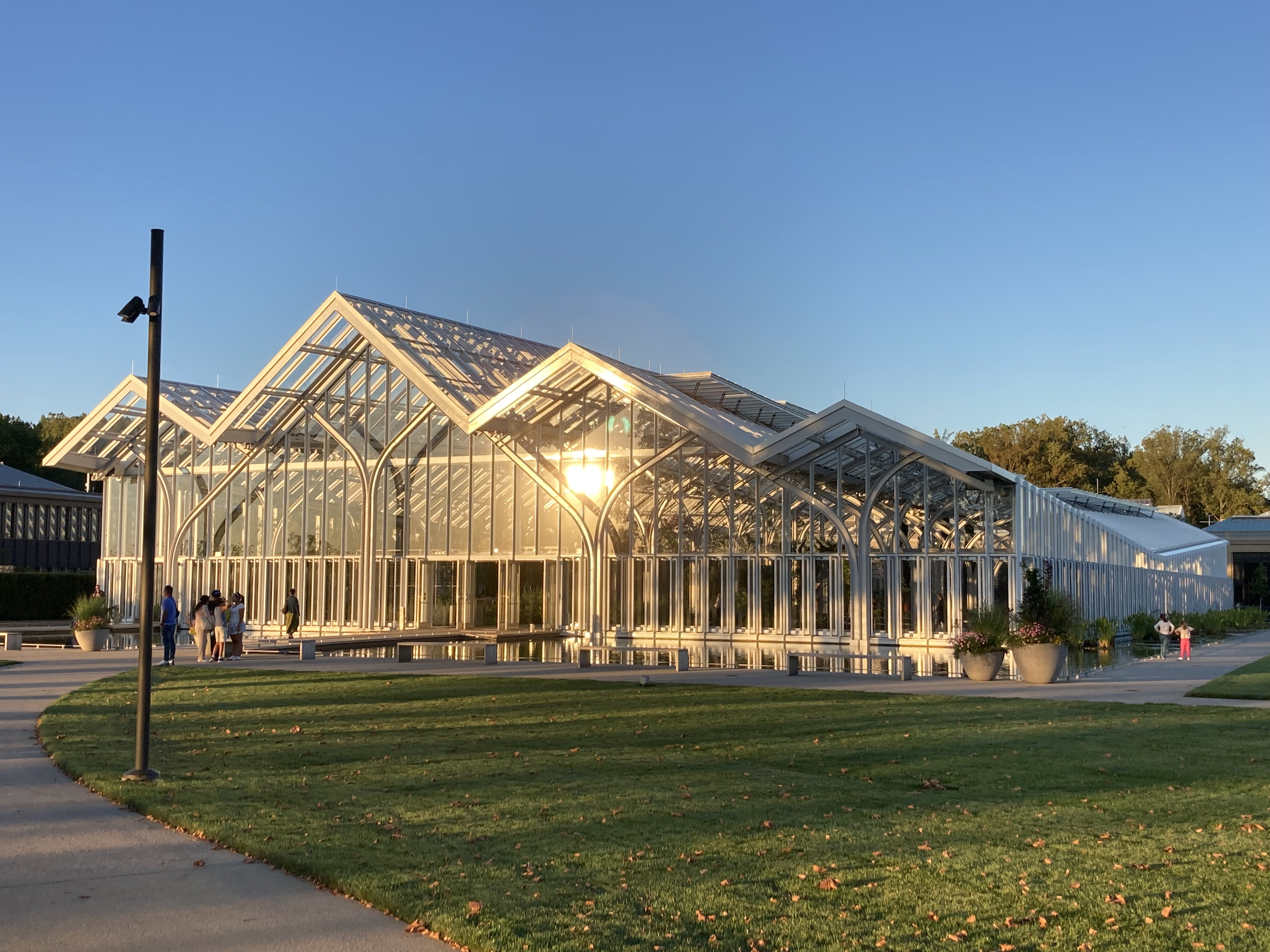 Victorian-style glass and white metal conservatory building photographed at golden hour.