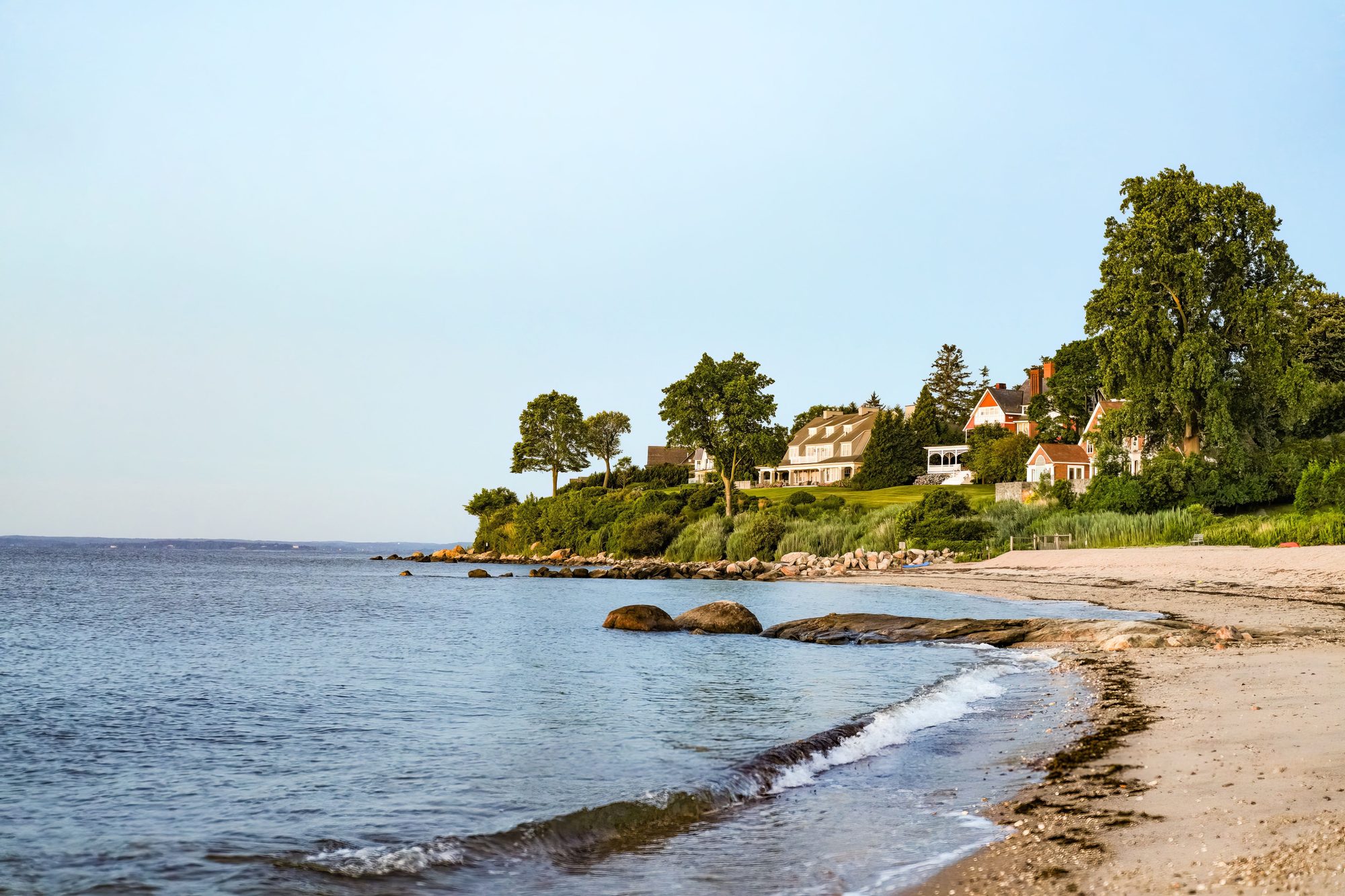 Charming seaside homes overlooking a tranquil sandy beach at sunset.