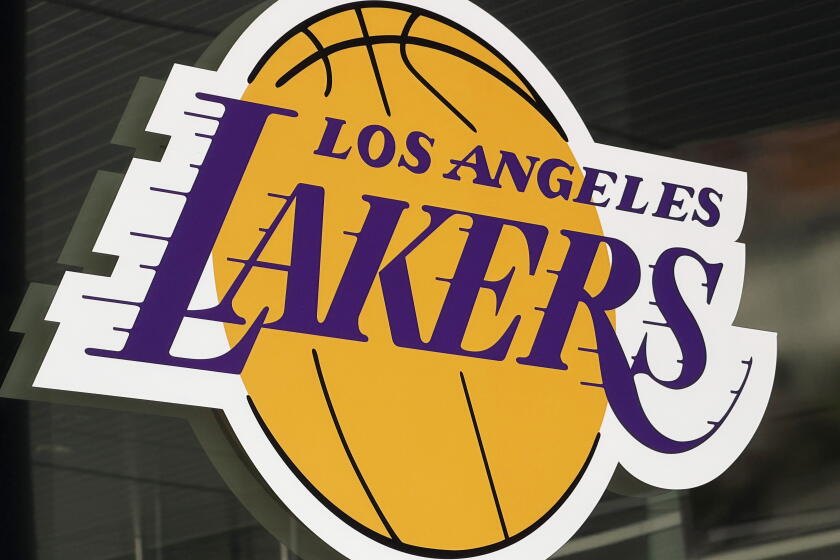 Gold and purple Los Angeles Lakers logo on a glass surface at an arena entrance.