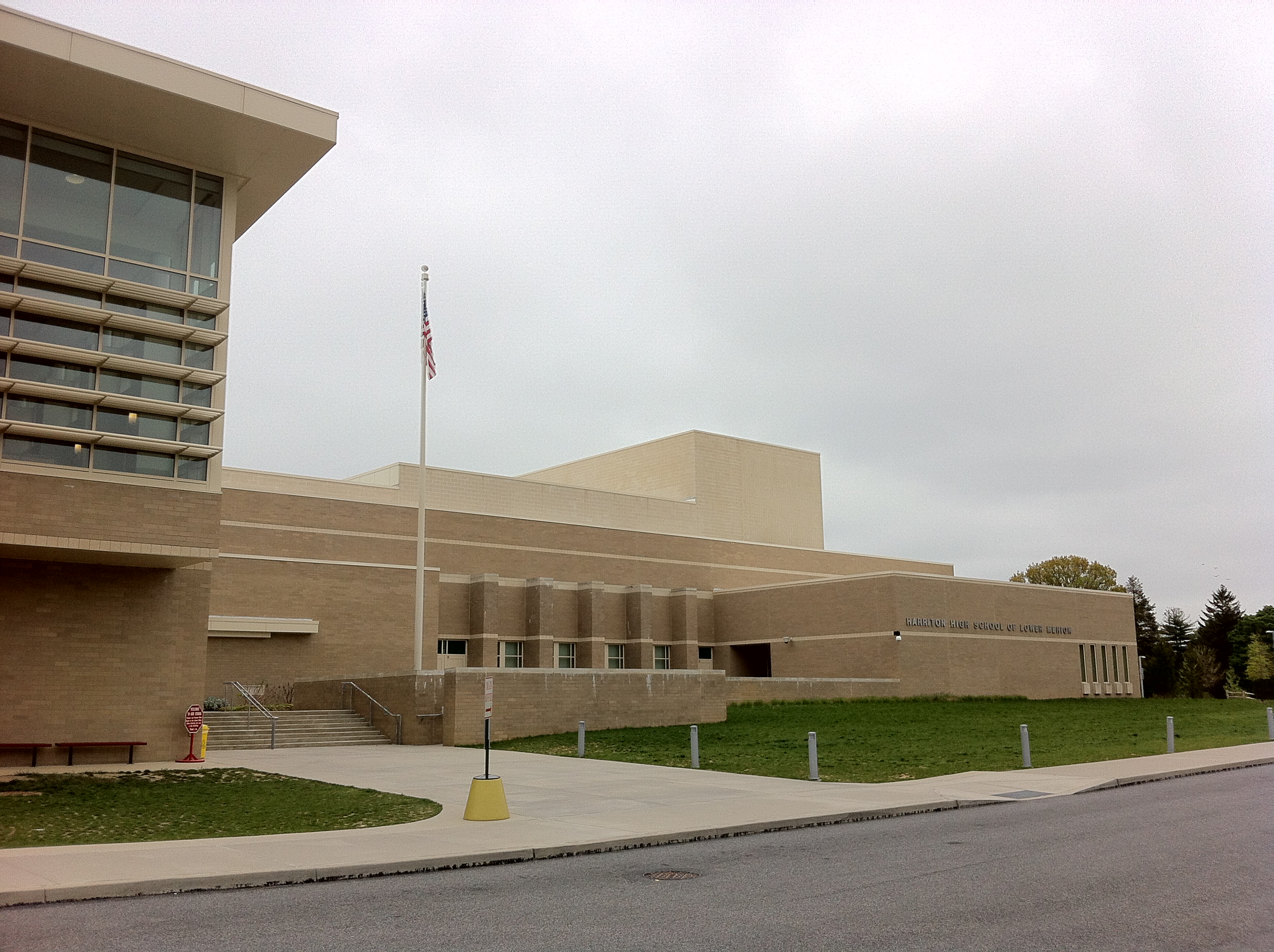 Exterior of a large tan brick school building with an American flag on a flagpole.