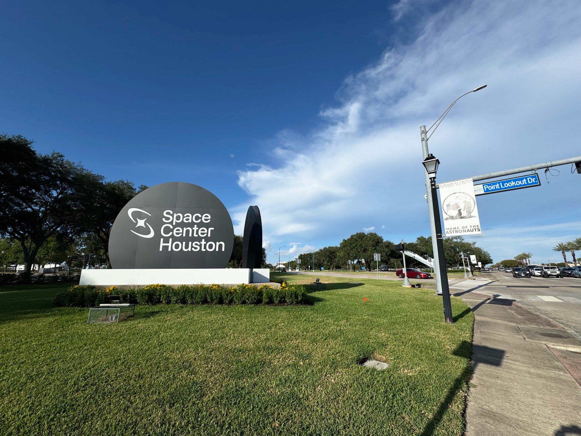 A sign at the road entrance to the official visitor center of NASA's Johnson Space Center.Signs and roads.Wide.