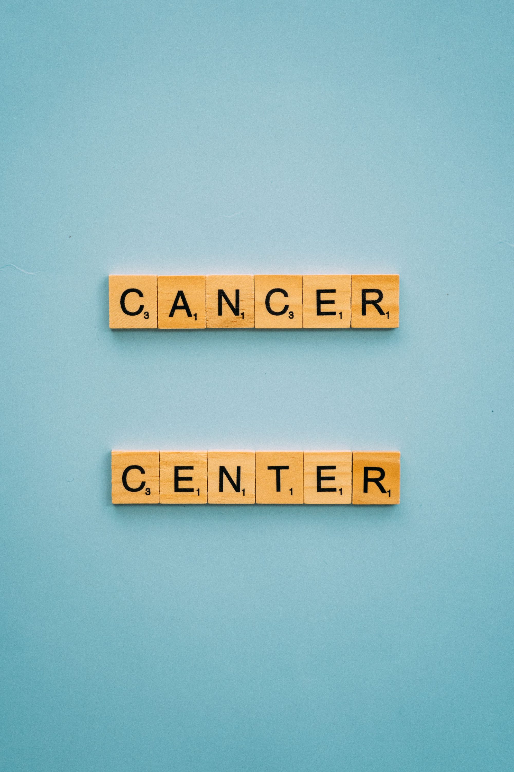 Scrabble tiles spelling 'Cancer Center' on a blue background, highlighting awareness.