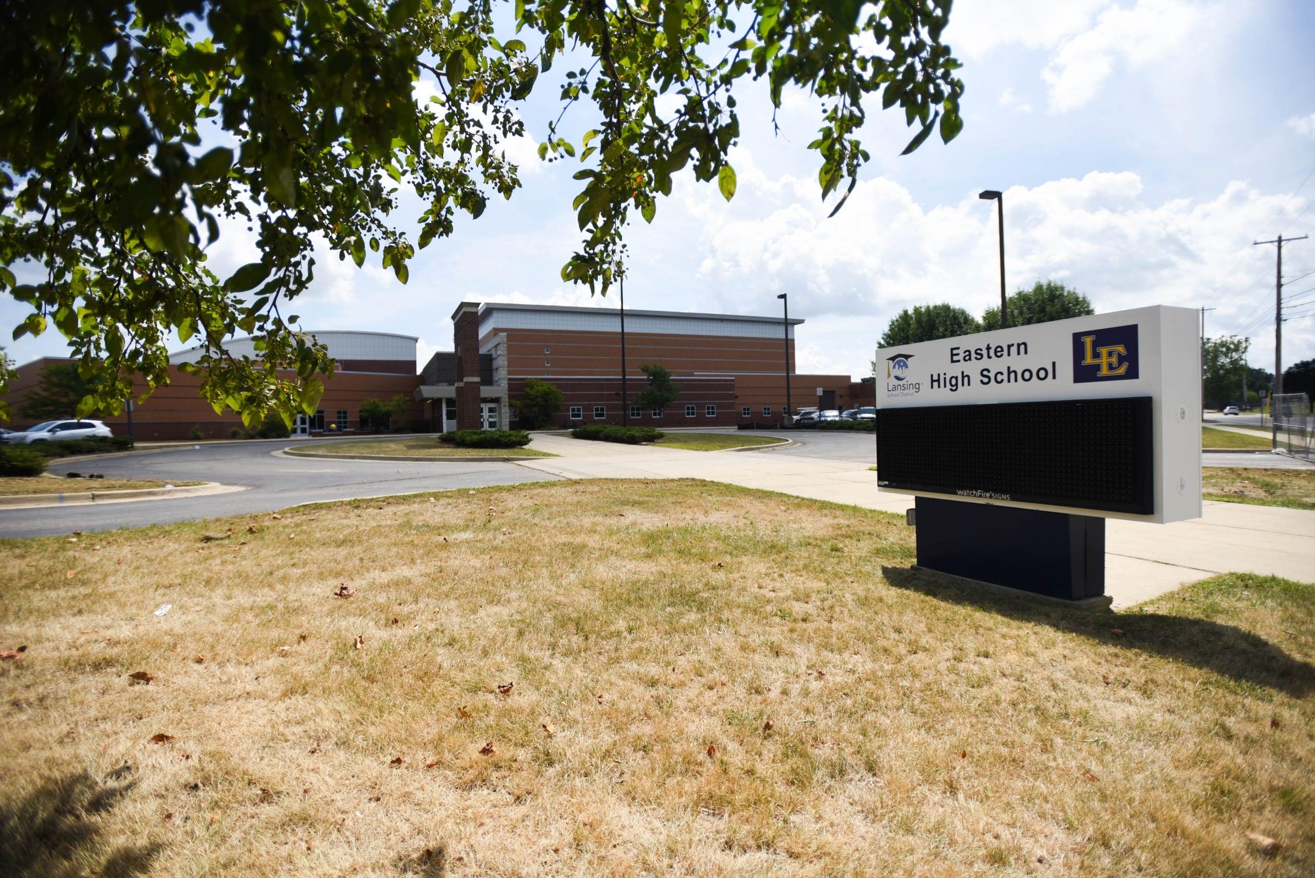 Exterior of a high school building with a sign reading Eastern High School and the Lansing School District logo.