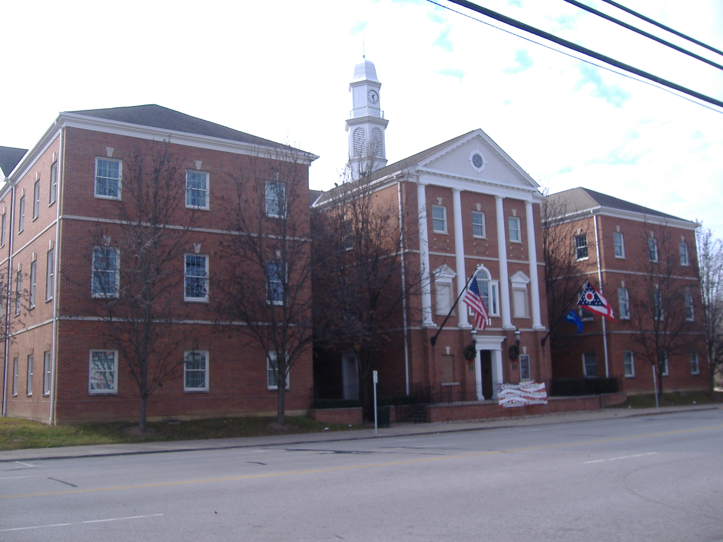 Red-brick government building with clock tower and columned entrance, American flag visible.
