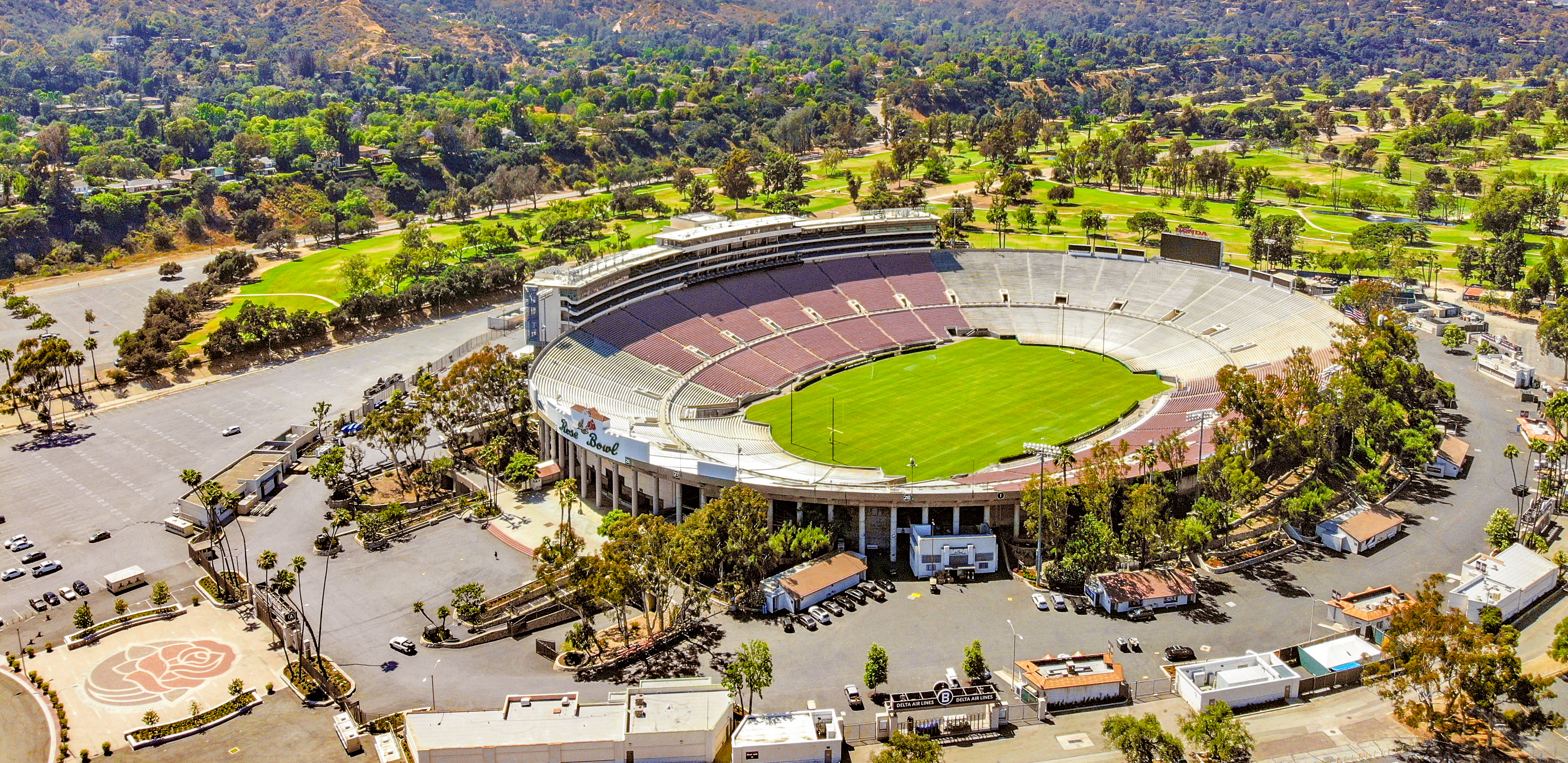 Aerial view of an oval stadium surrounded by trees and hills.
