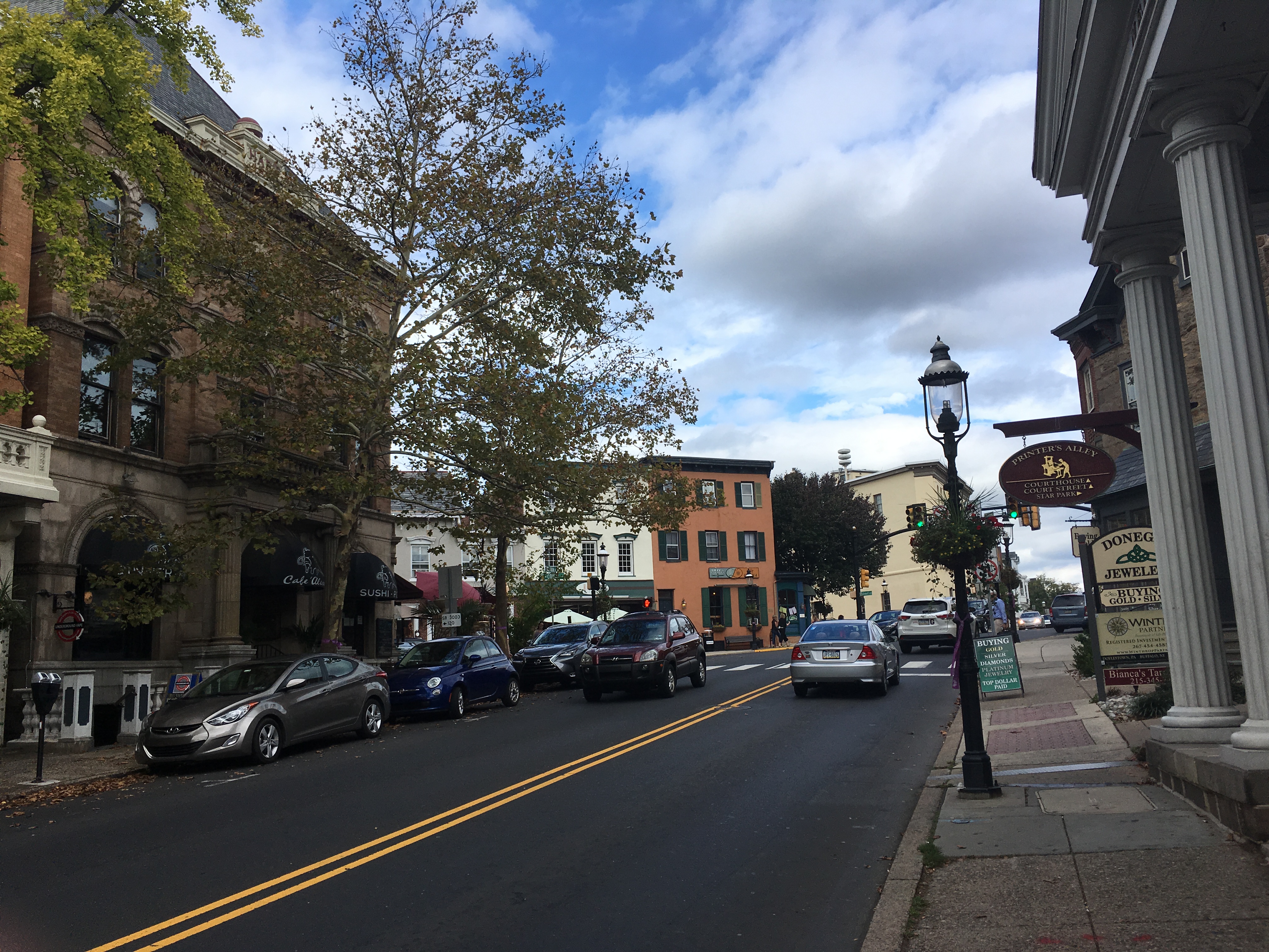 Two-lane downtown street with brick commercial buildings and a decorative street lamp.