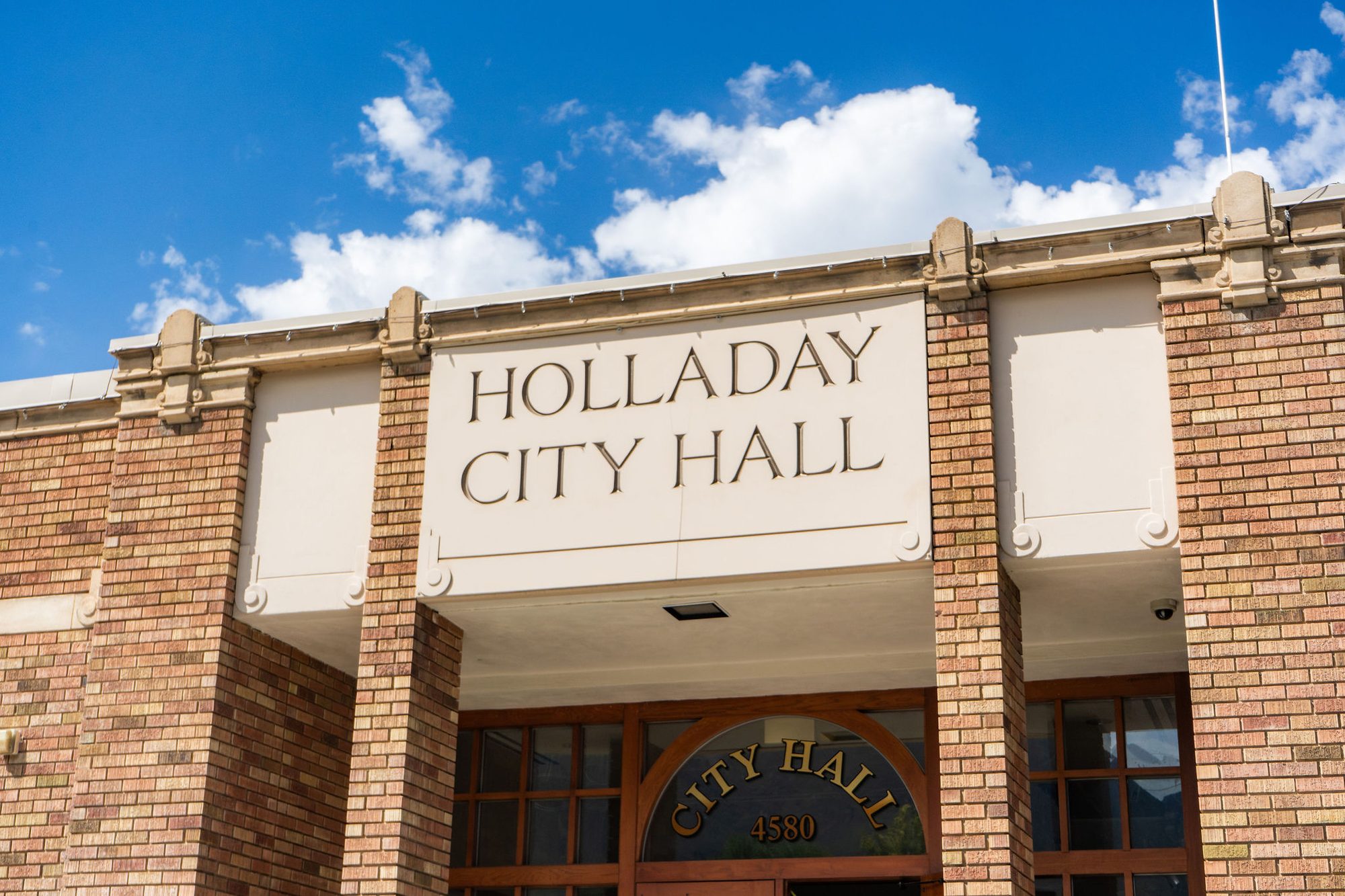 Brick city hall building exterior with raised name lettering above entrance doors.