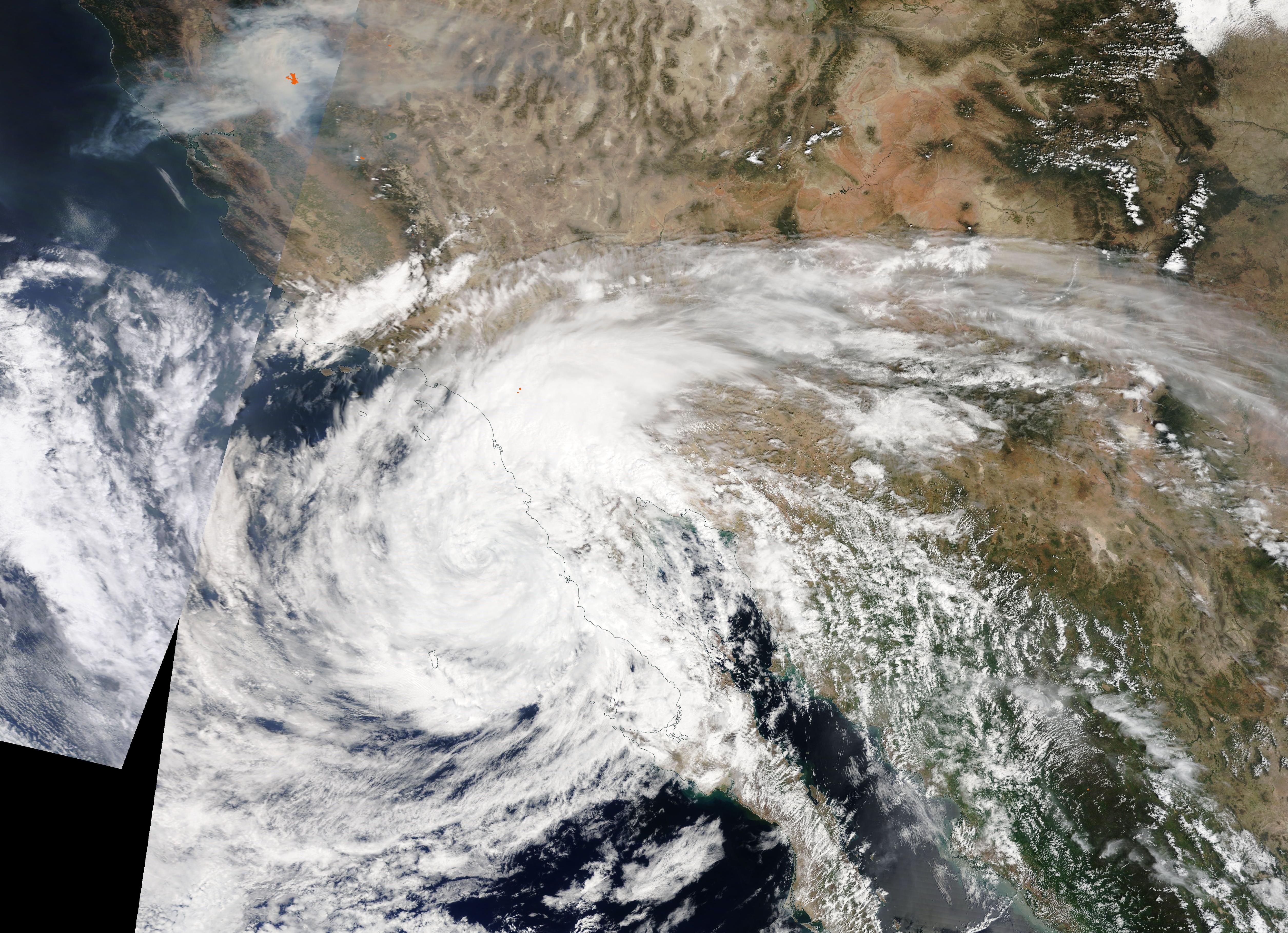 Satellite view of a tropical storm approaching the Southern California coast with spiral cloud bands.