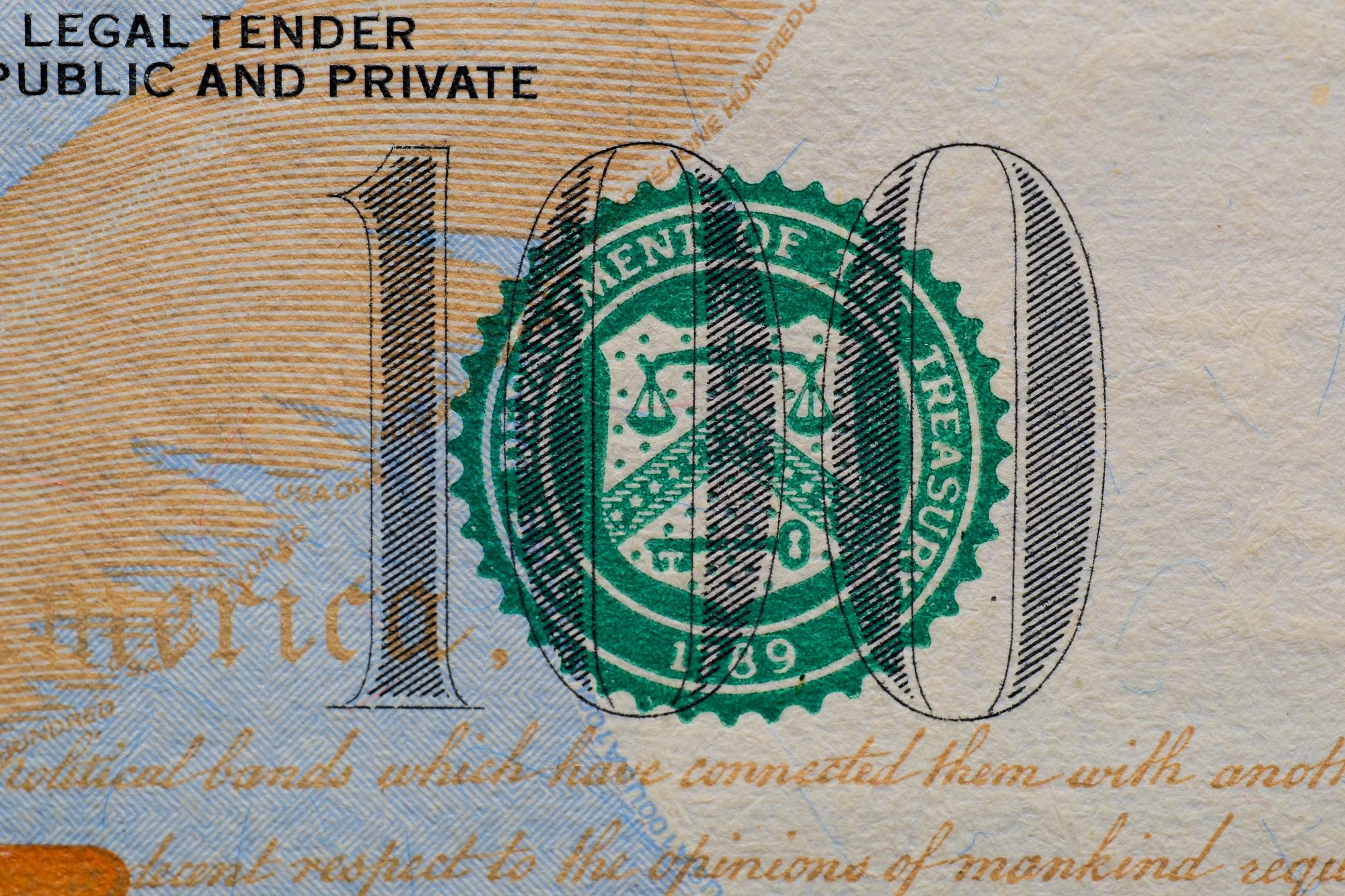 Detailed view of the US 100 dollar bill showing the Treasury seal and printed text.