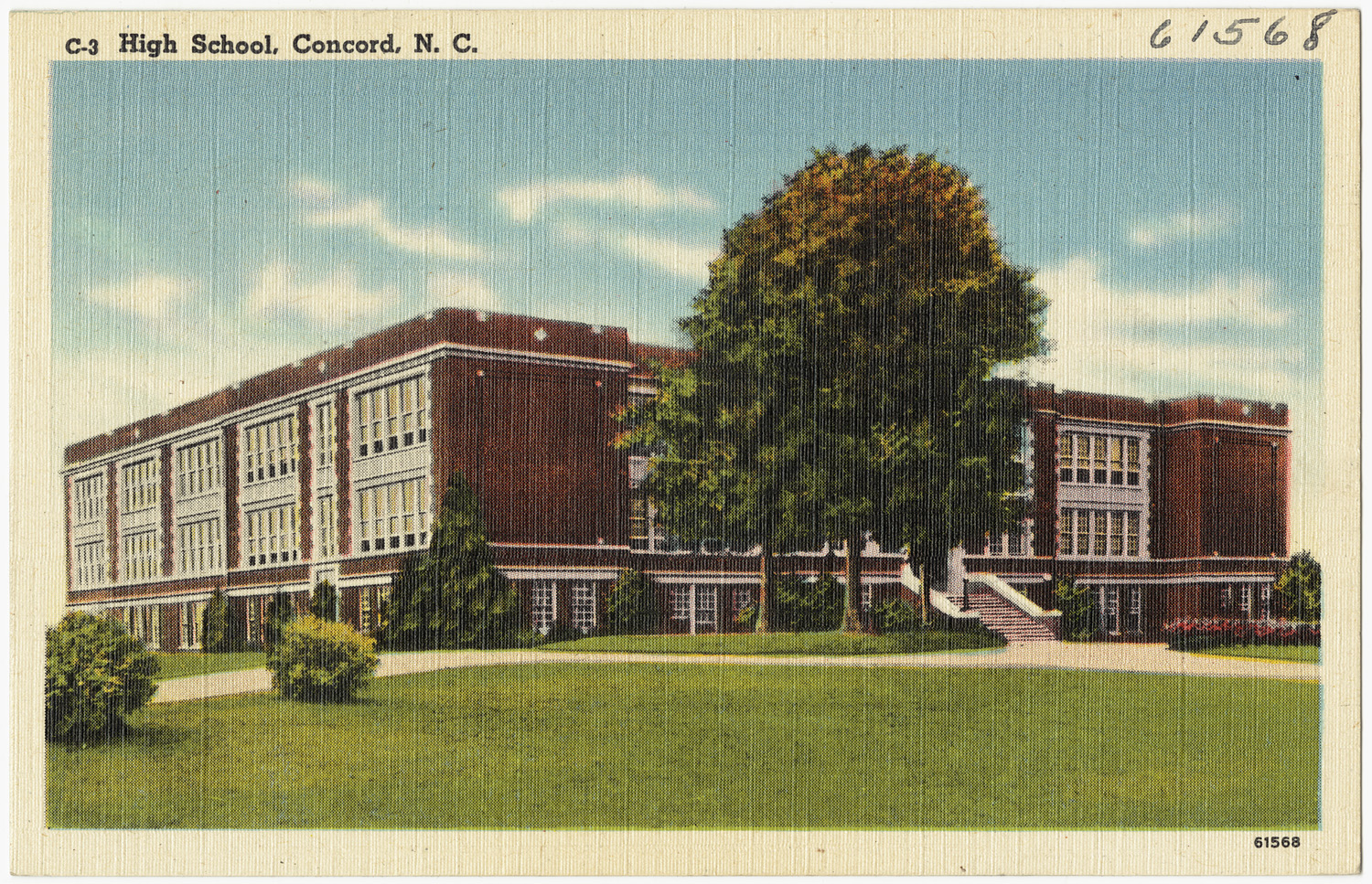 Multi-story brick school building with lawn and large trees, vintage postcard.