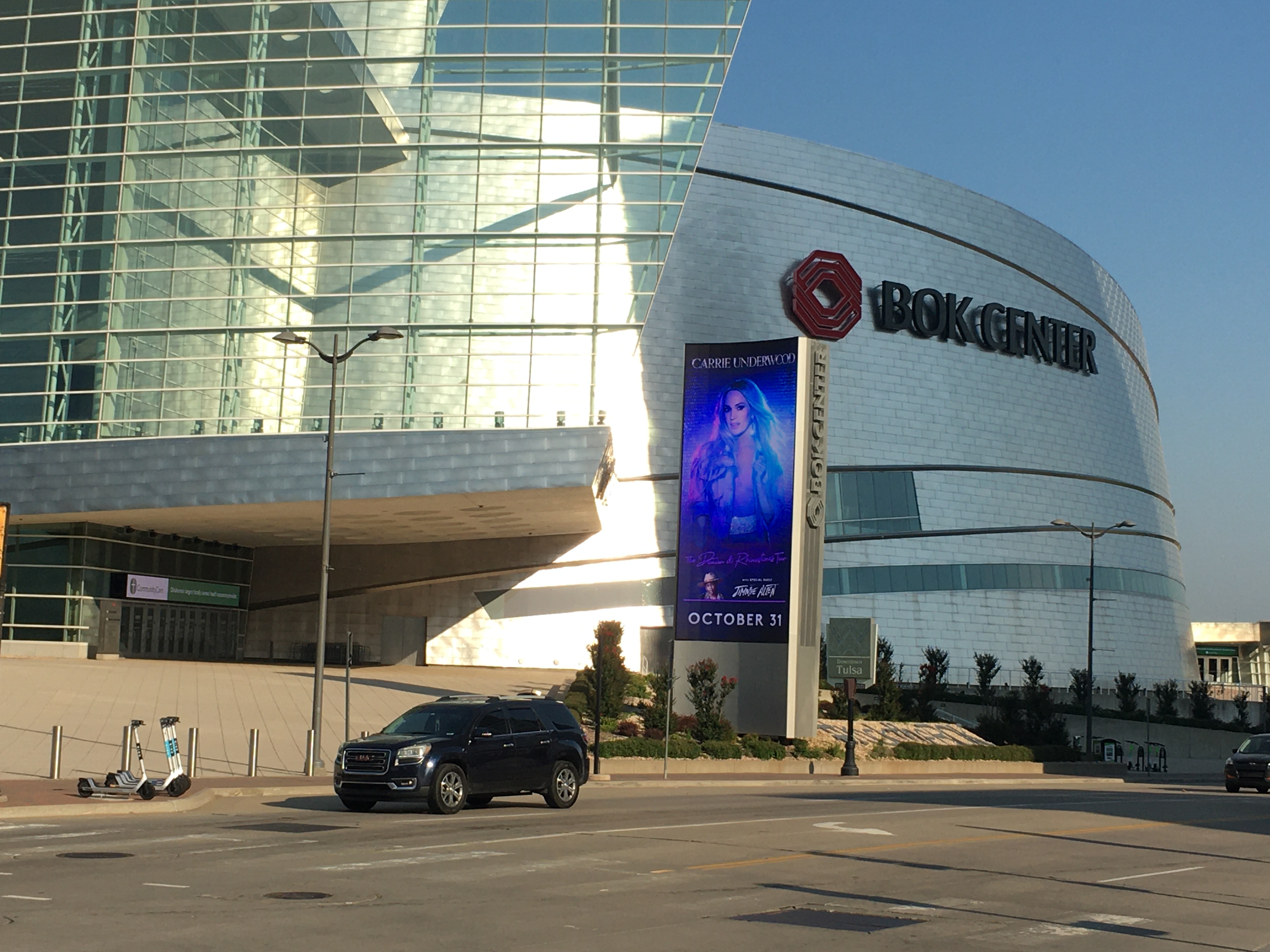 Exterior of a large curved glass-and-steel arena on a clear morning.