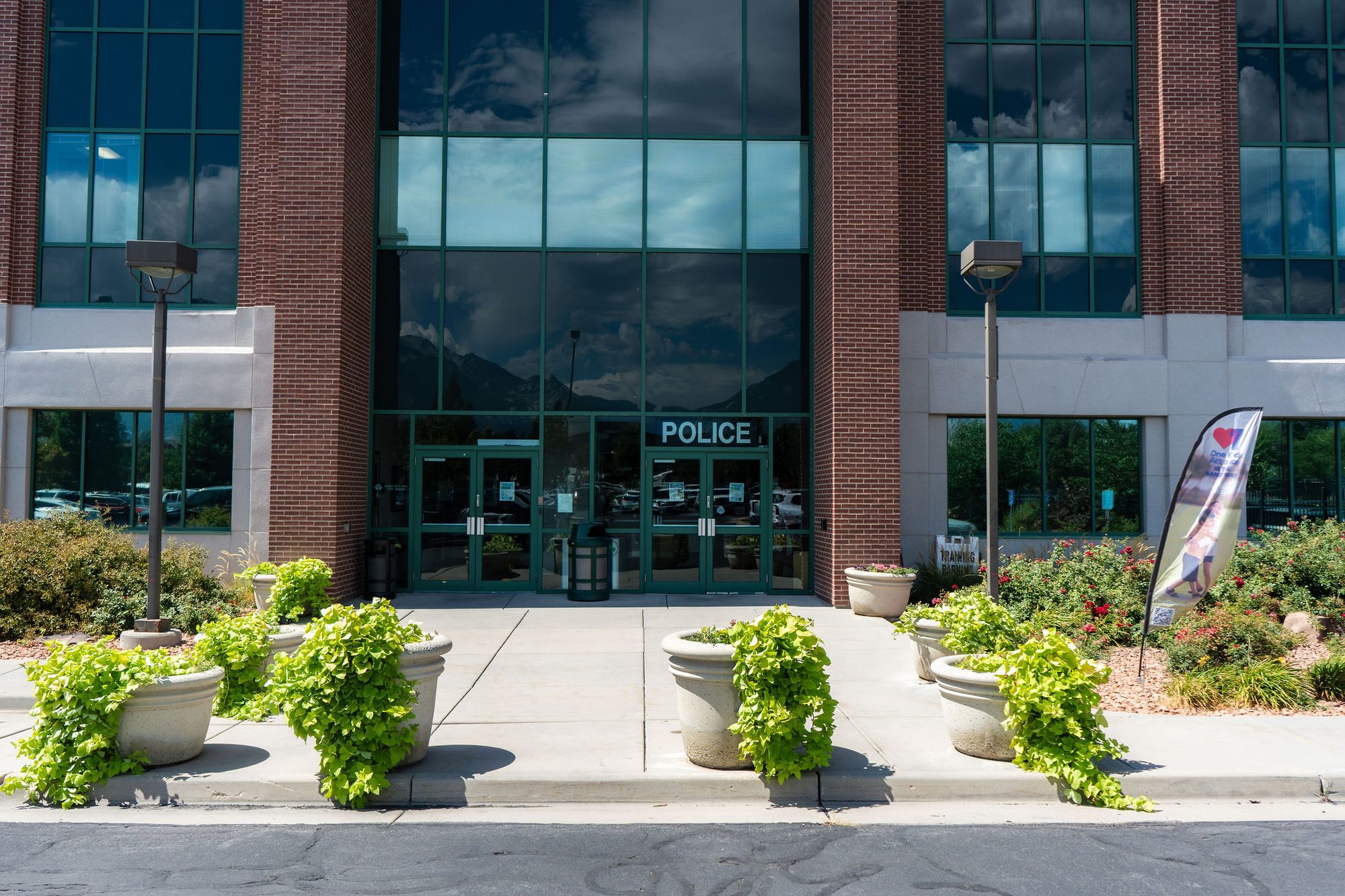 Brick police station entrance with glass doors and concrete planters