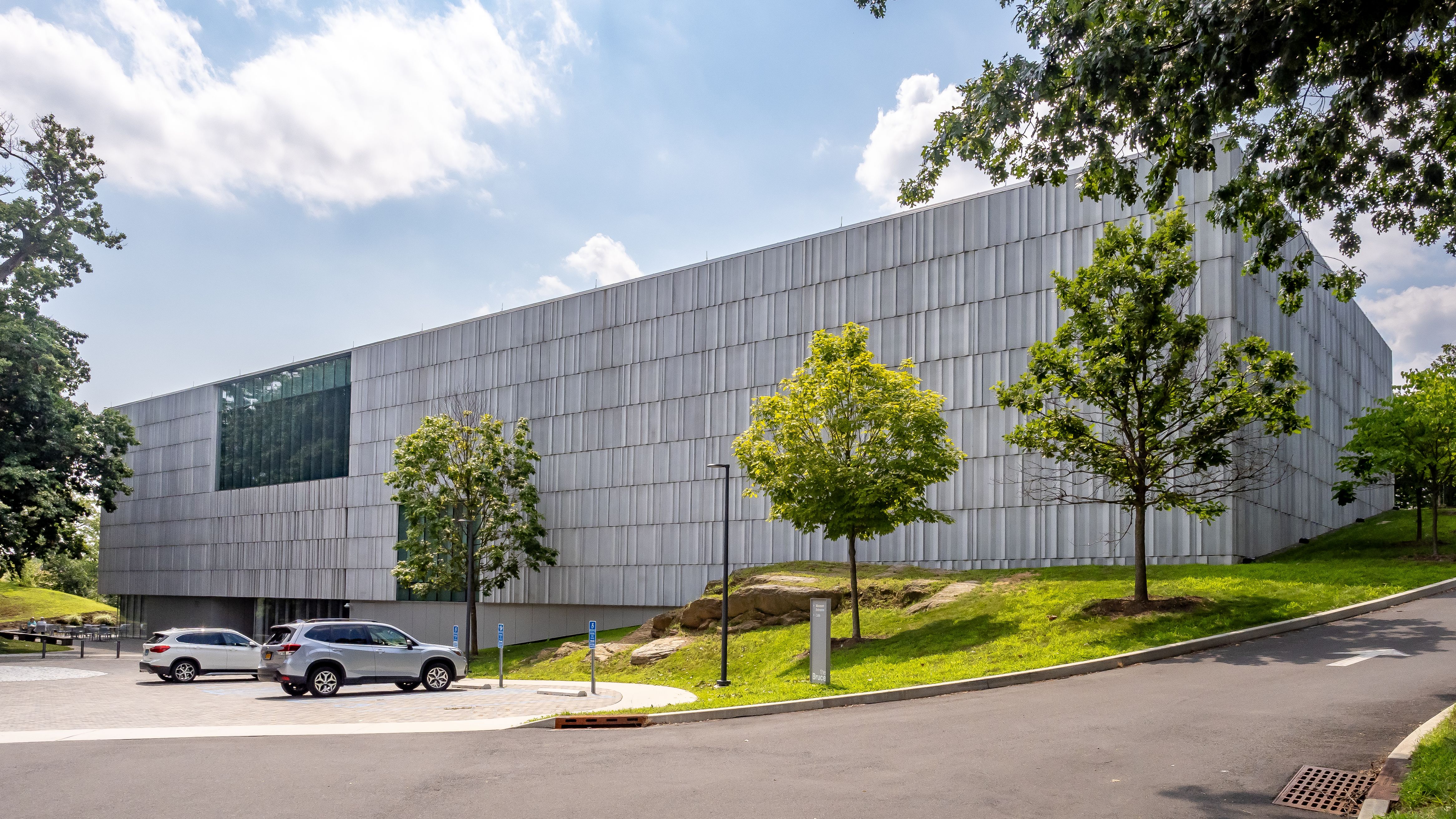 Modern museum building with ribbed facade and large glass windows surrounded by trees.