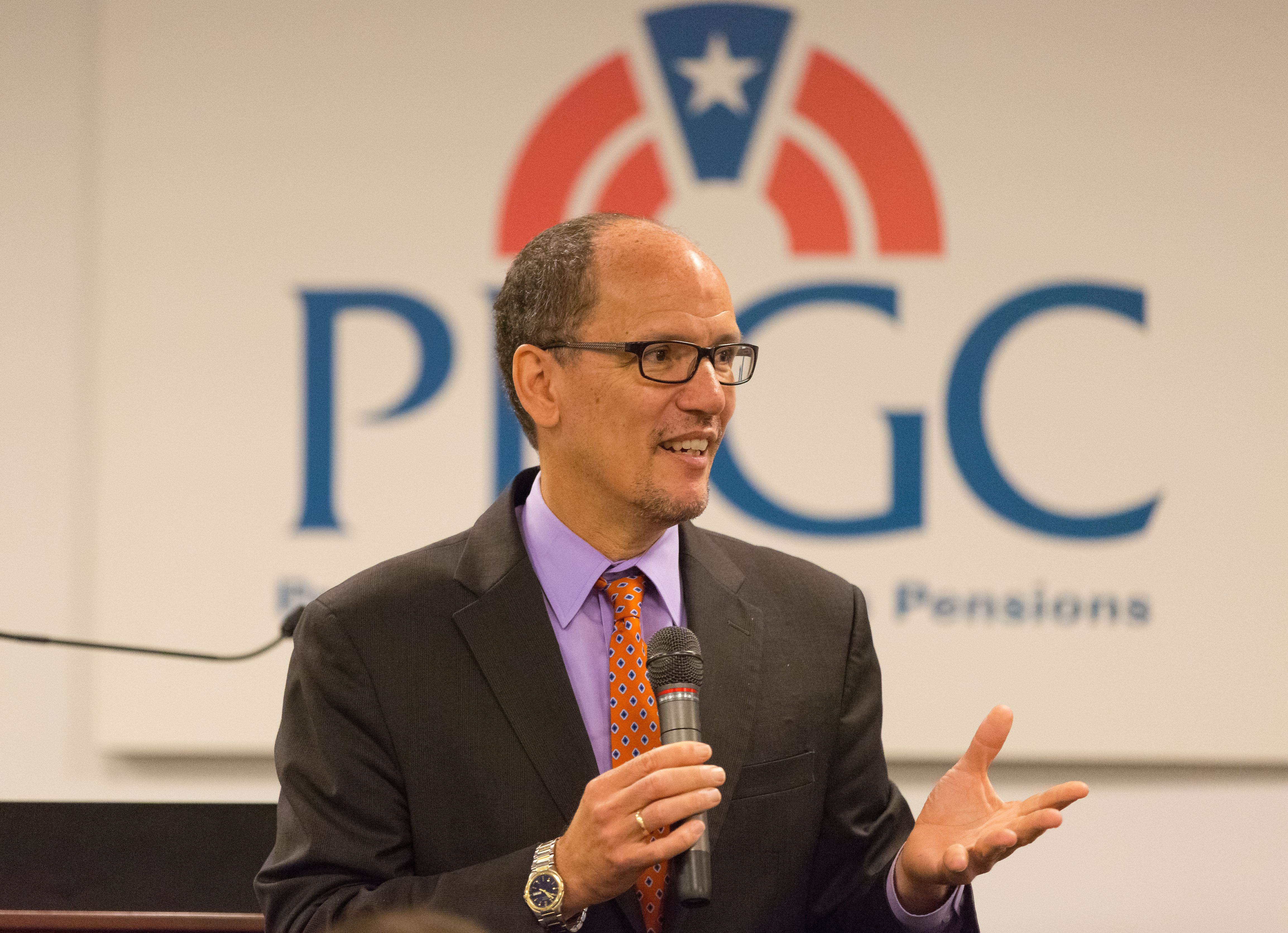 Man in dark suit speaking at a podium in front of a PBGC logo backdrop.