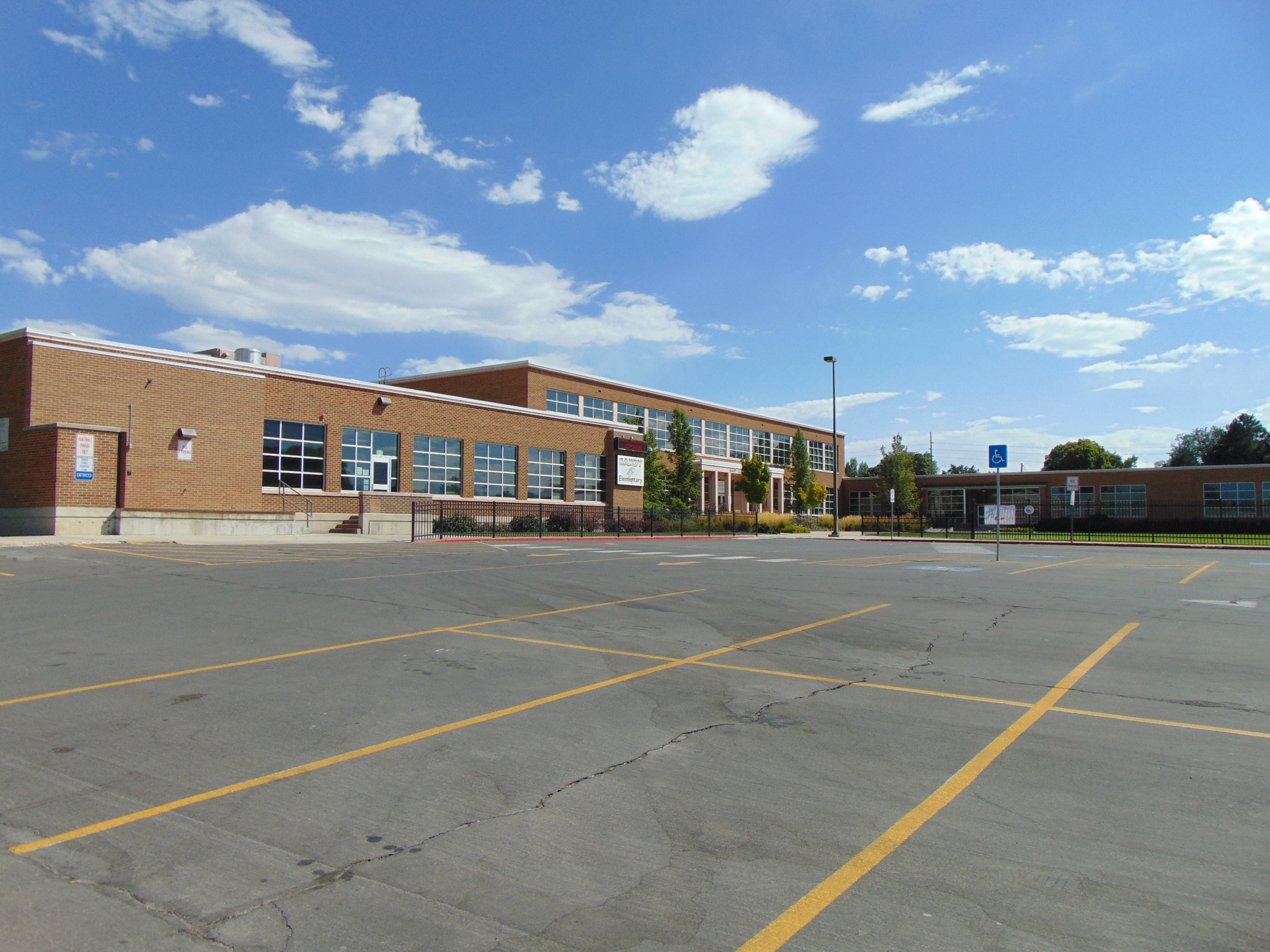 Exterior of a two-story brick elementary school building under a partly cloudy sky.