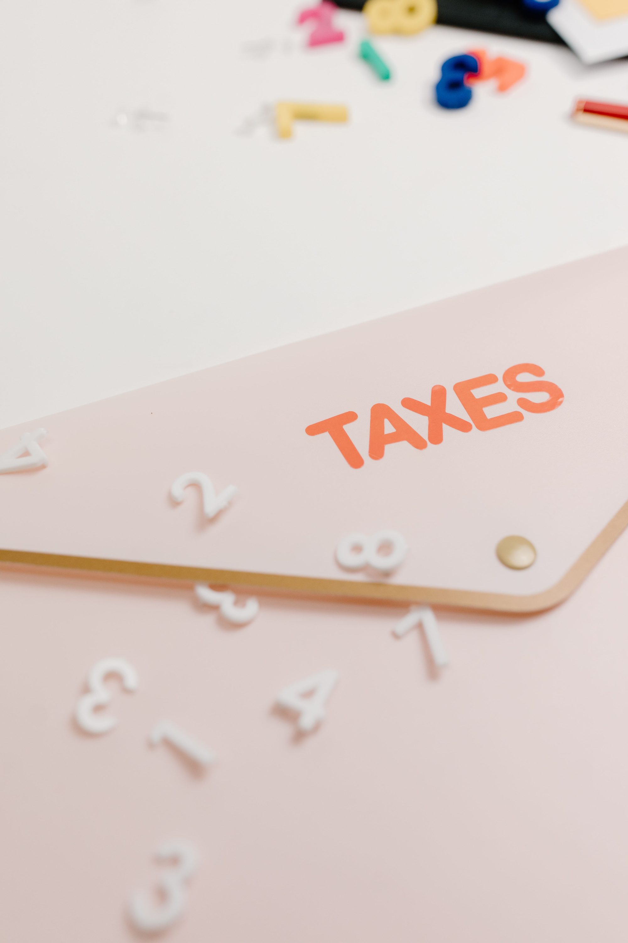 A conceptual image of a pink envelope labeled 'Taxes' with scattered numbers, symbolizing tax calculations.