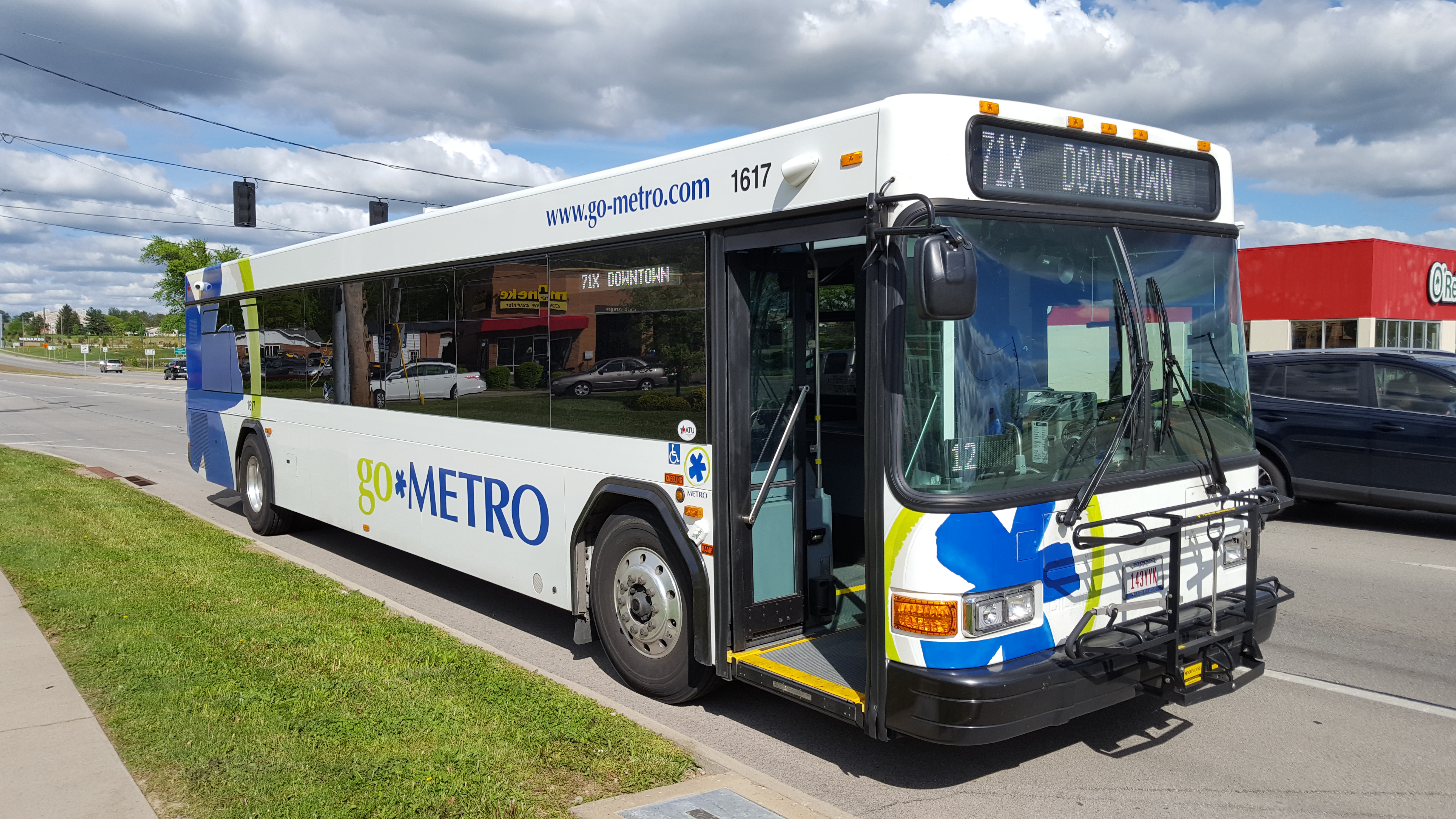 A white Go Metro transit bus stopped with its doors open at a curb.