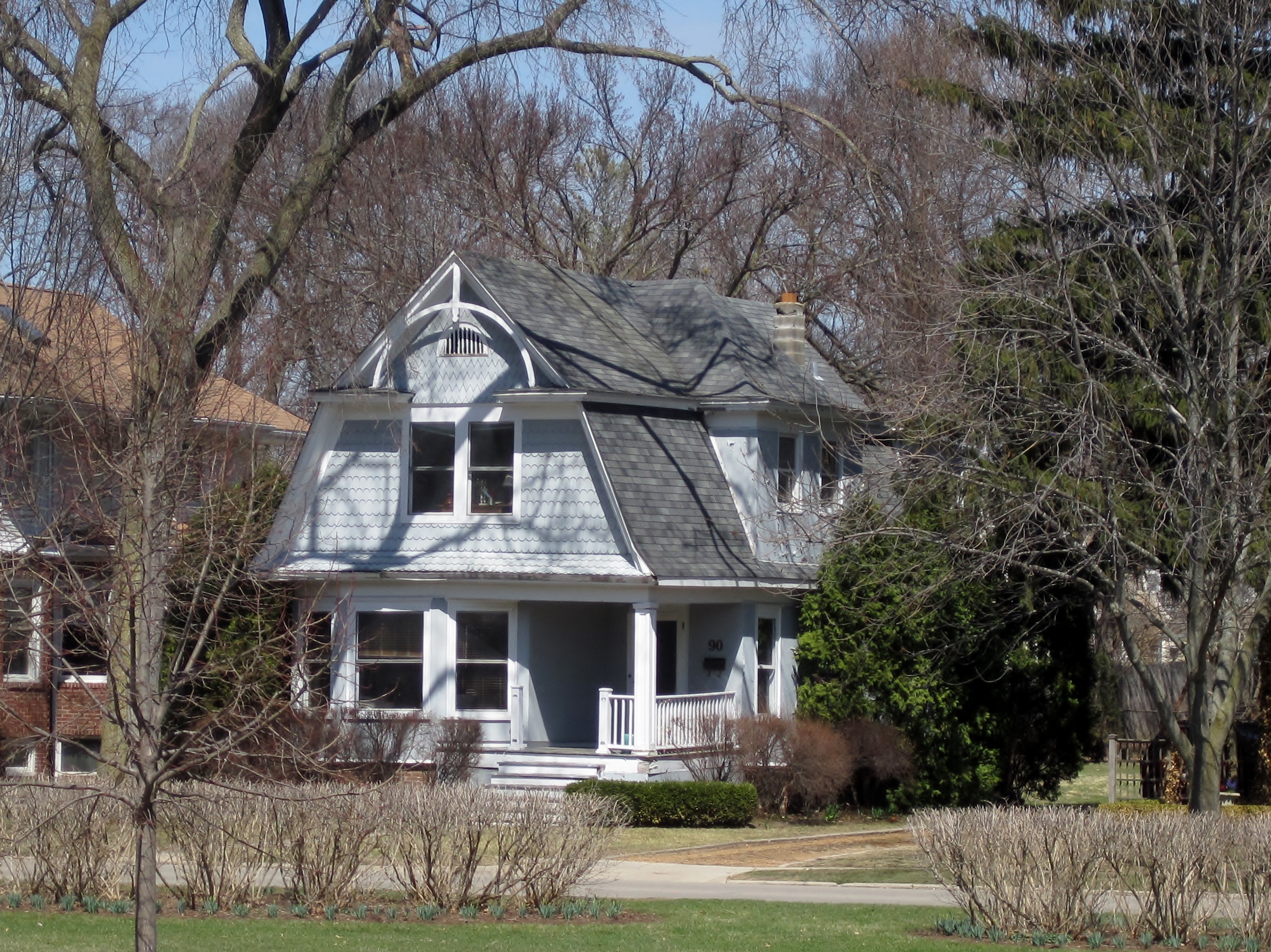 A Victorian-era home with a mansard roof and front porch on a tree-lined lot.