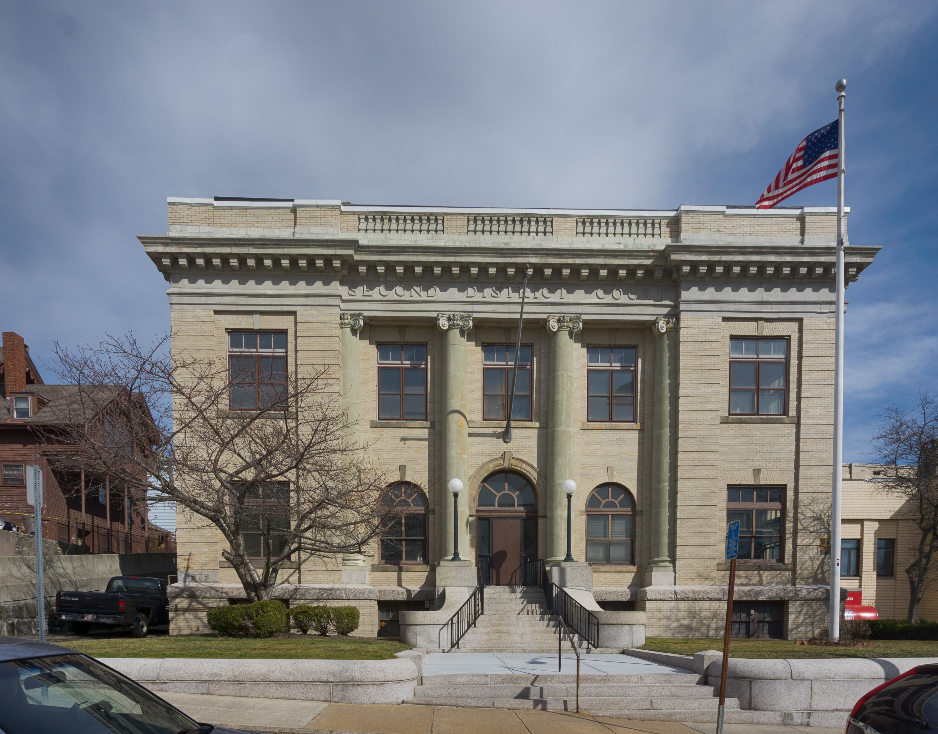 Neoclassical two-story courthouse with columns and an American flag out front.