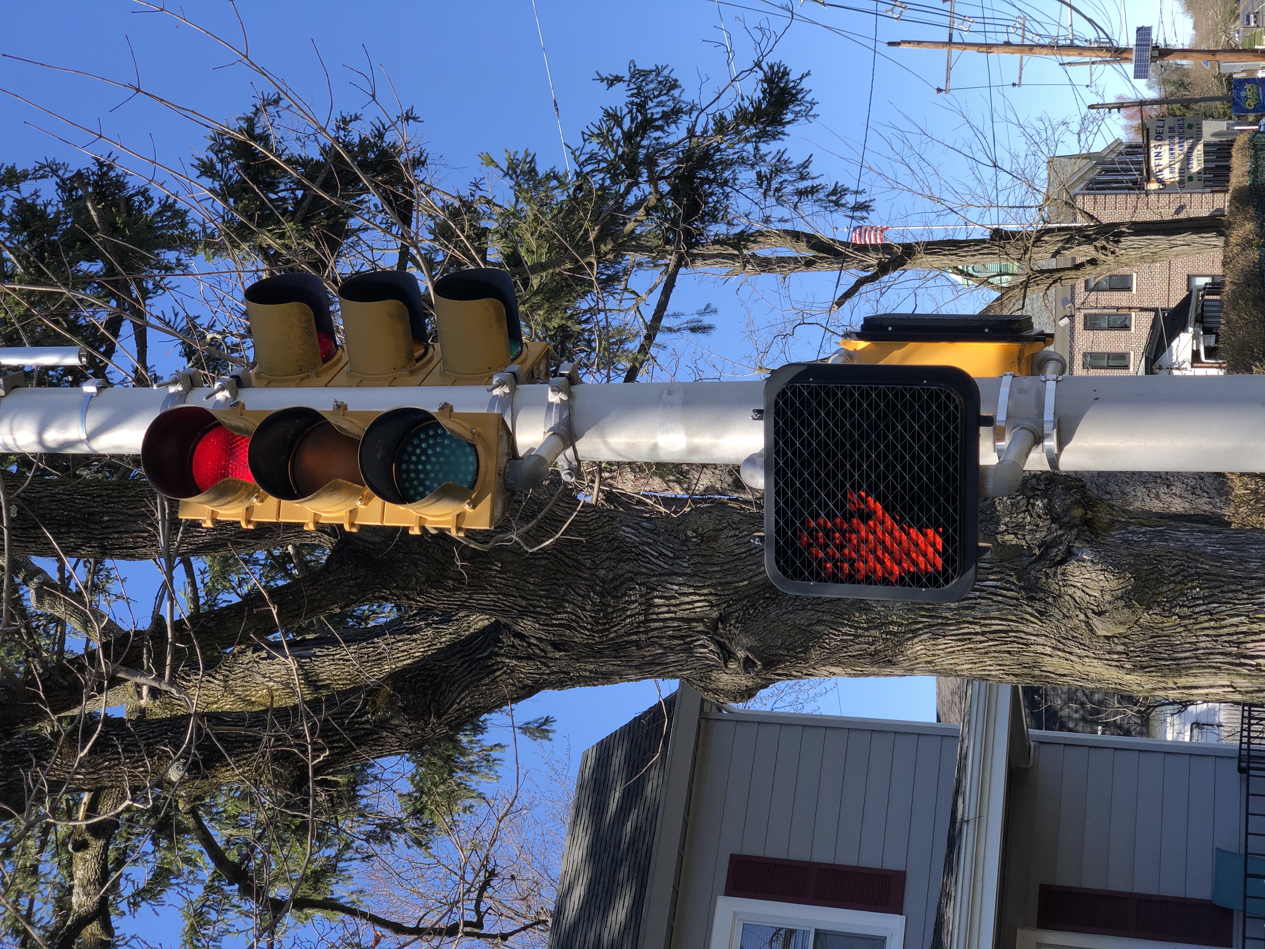 Red traffic light and orange no-walk pedestrian hand signal on a white pole.
