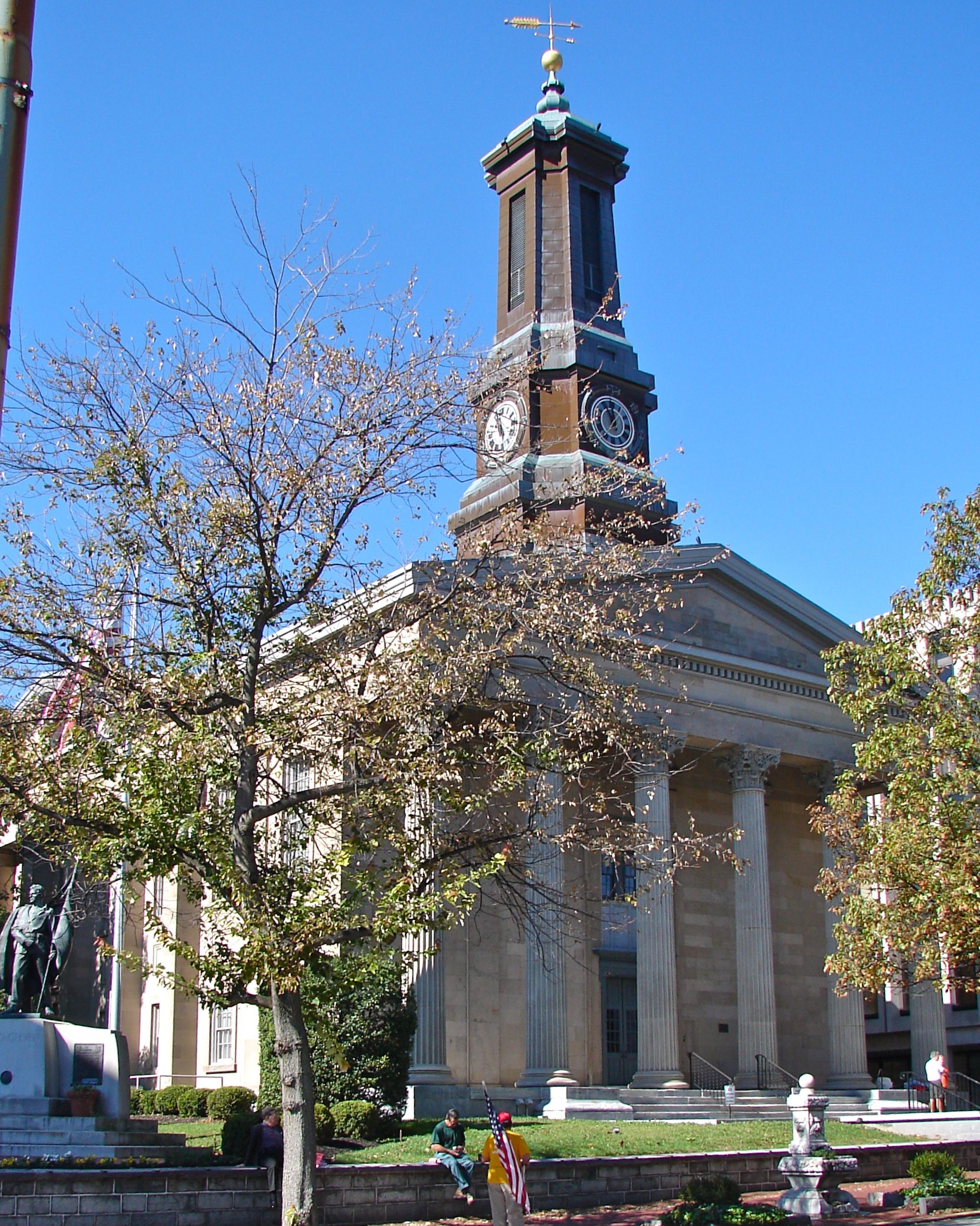 Neoclassical courthouse with a tall clock tower and large columns under a clear blue sky.
