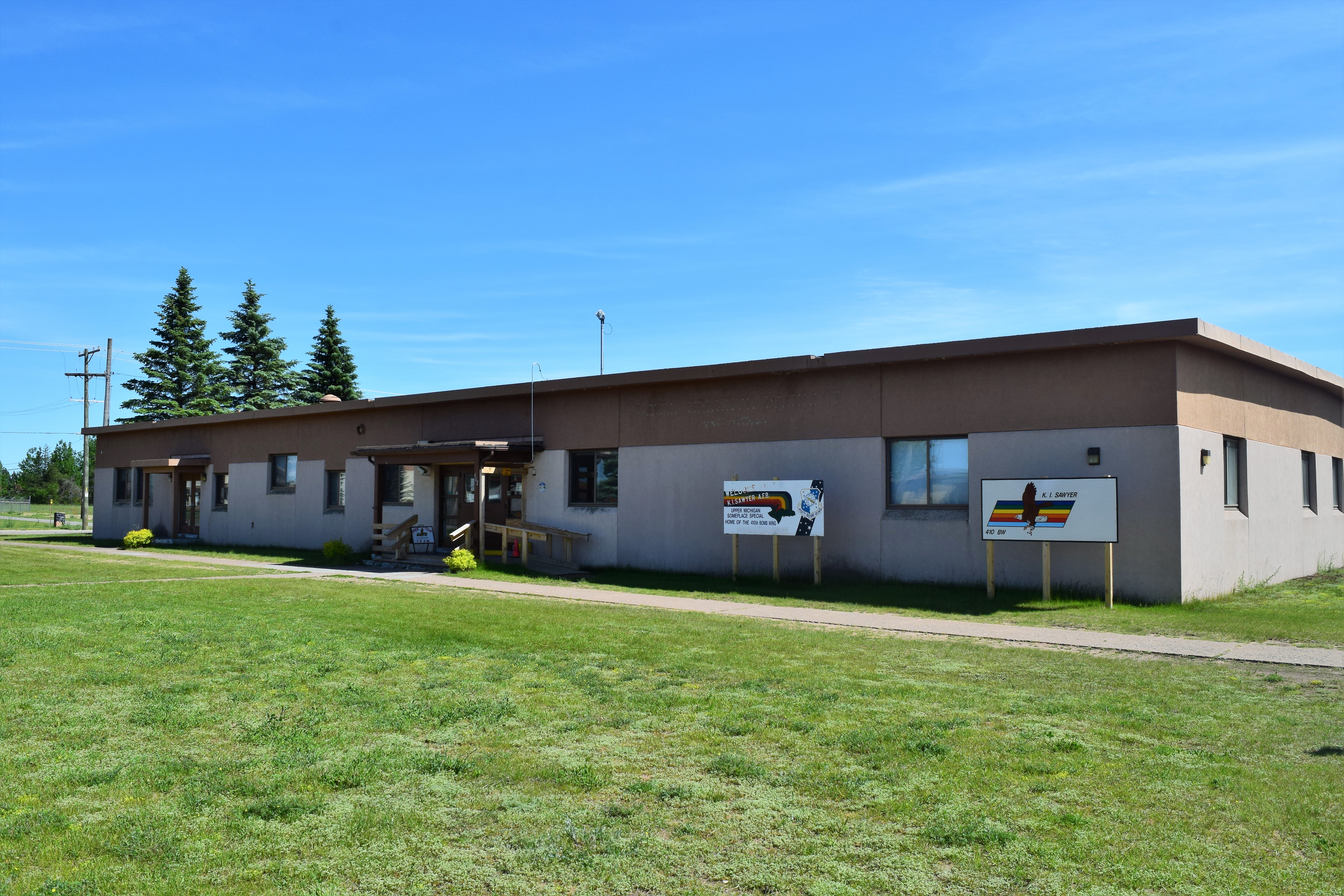 Low single-story building with flat roof and green lawn on a sunny day.