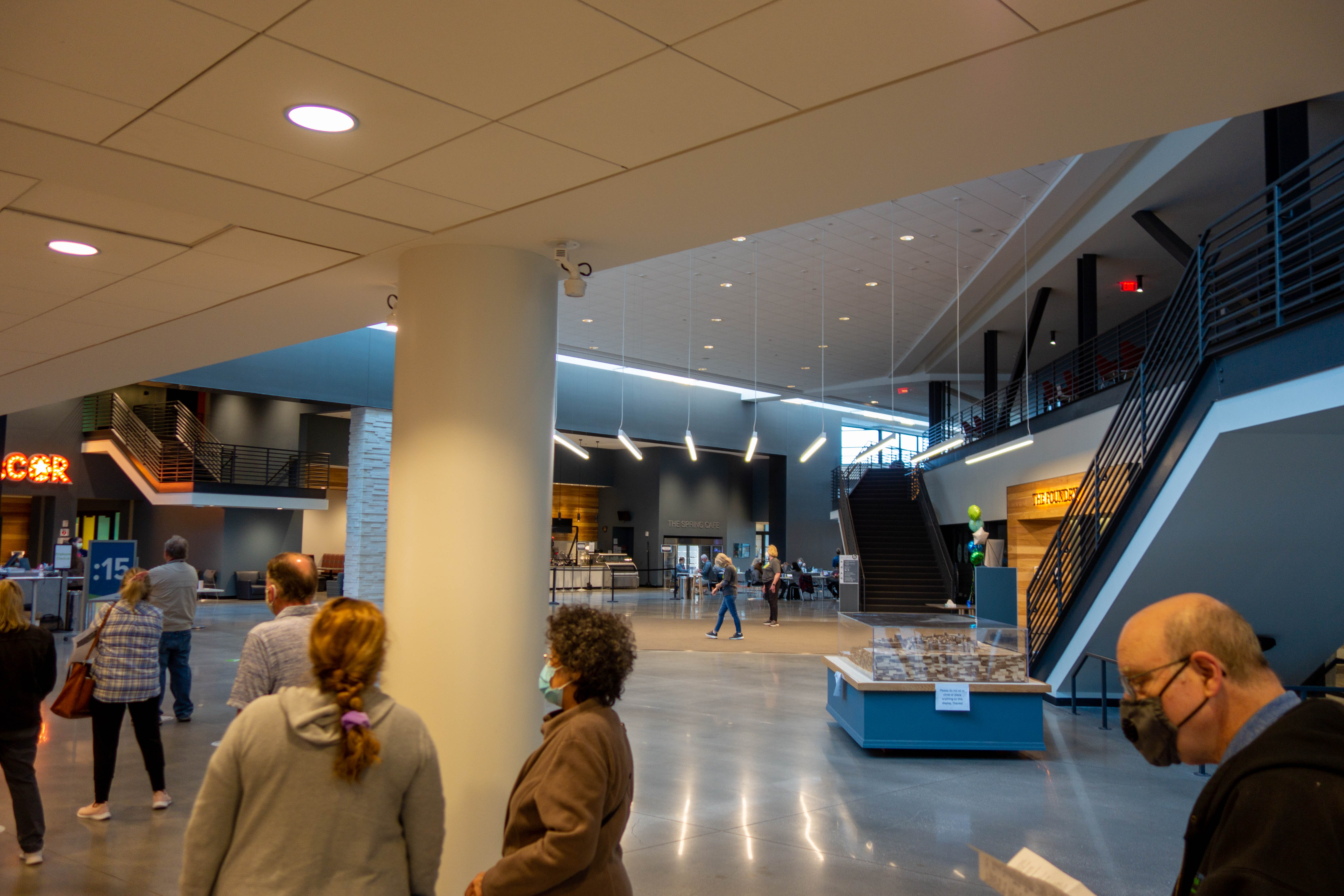 People standing in a large modern building lobby during a community vaccine clinic.