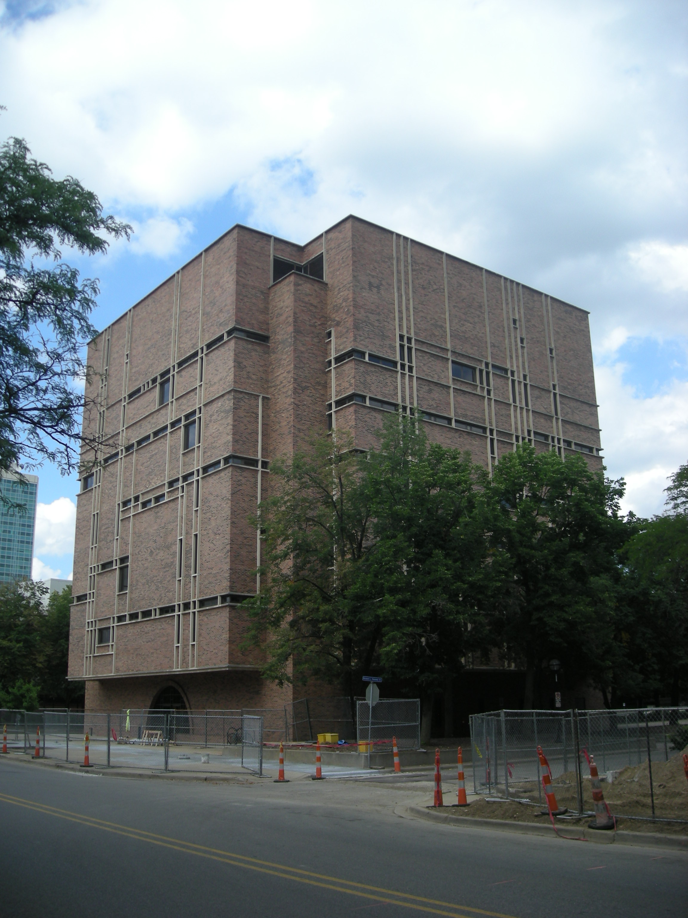 Multi-story brutalist brick building surrounded by trees on a university campus.