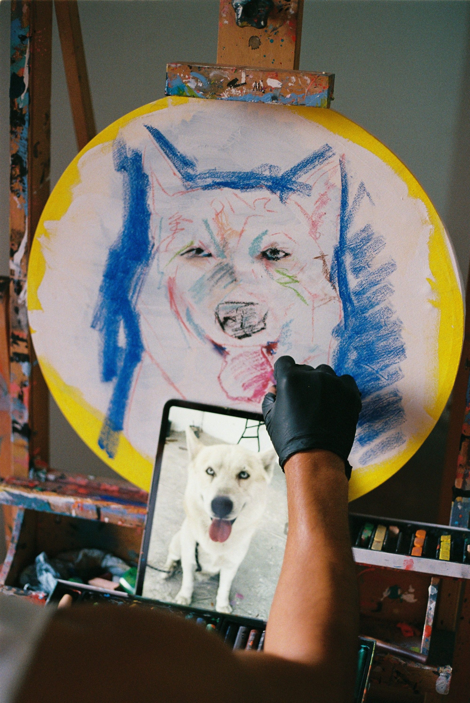 Artist replicates dog photo into vibrant canvas sketch in studio.