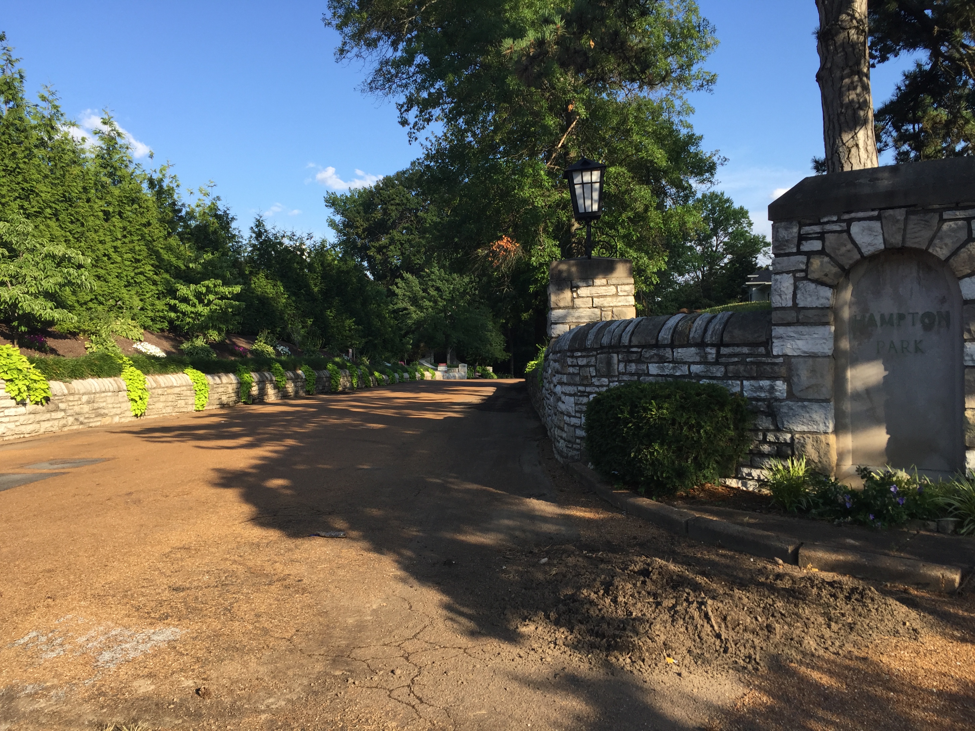 Stone entrance gate with lantern post at a tree-lined county park