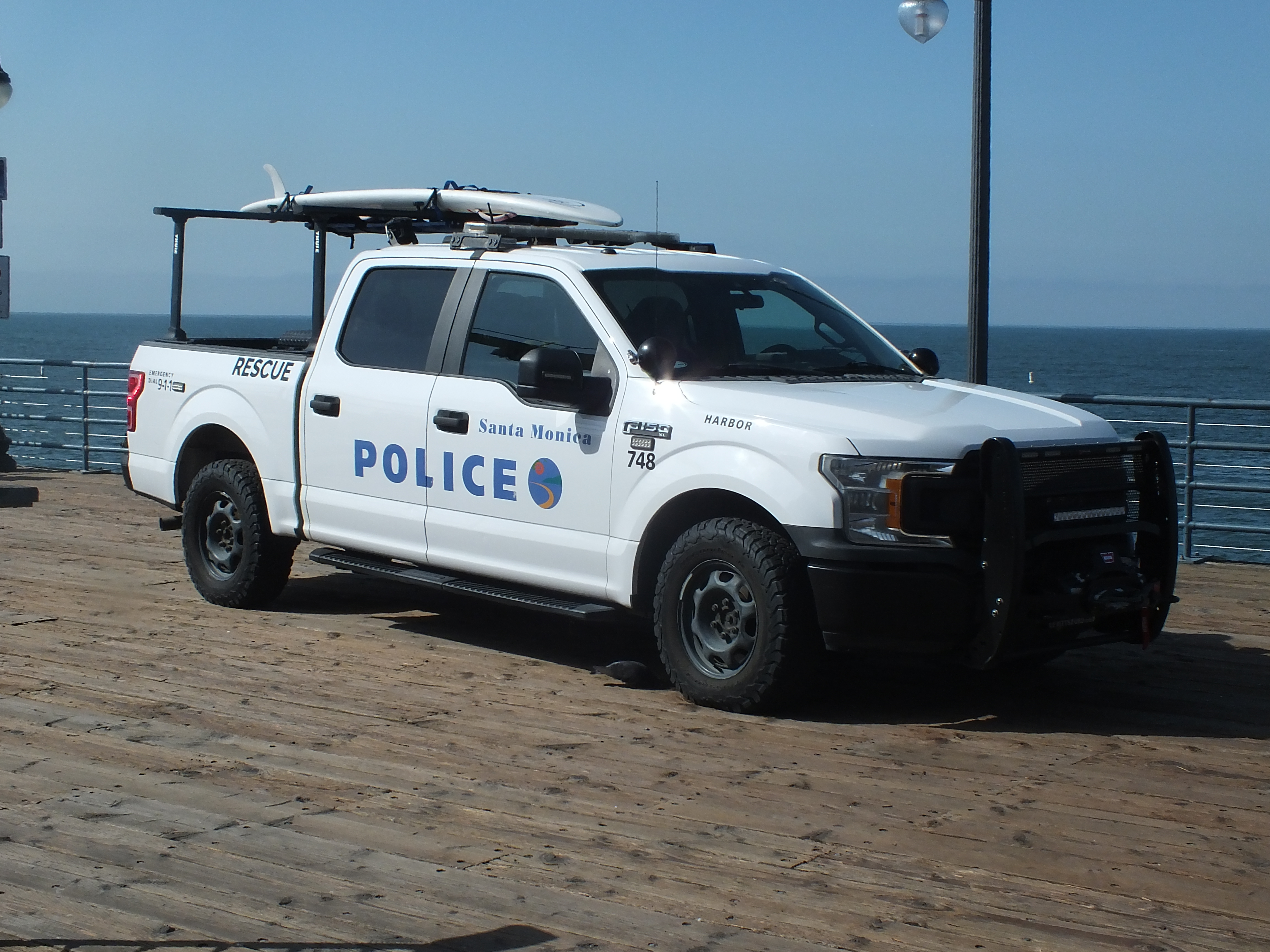 White Santa Monica Police Department pickup truck marked Harbor Unit parked on a pier.
